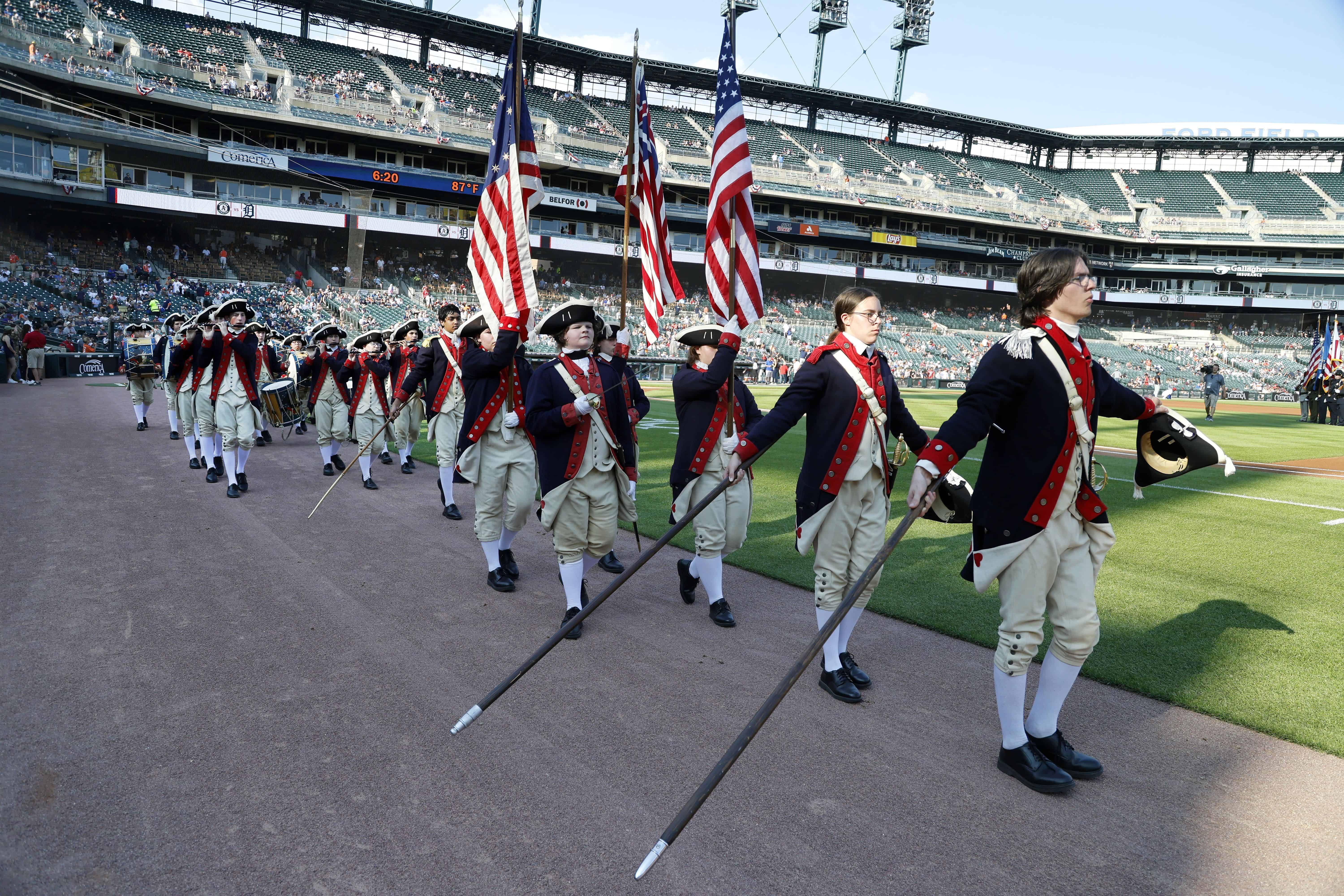 El Plymouth Fife and Drum Corps, de Plymouth, Michigan, entretiene a los aficionados antes del partido de béisbol de los Tigres de Detroit contra los Atléticos de Oakland por el Día de la Independencia, el martes 4 de julio de 2023, en Detroit.