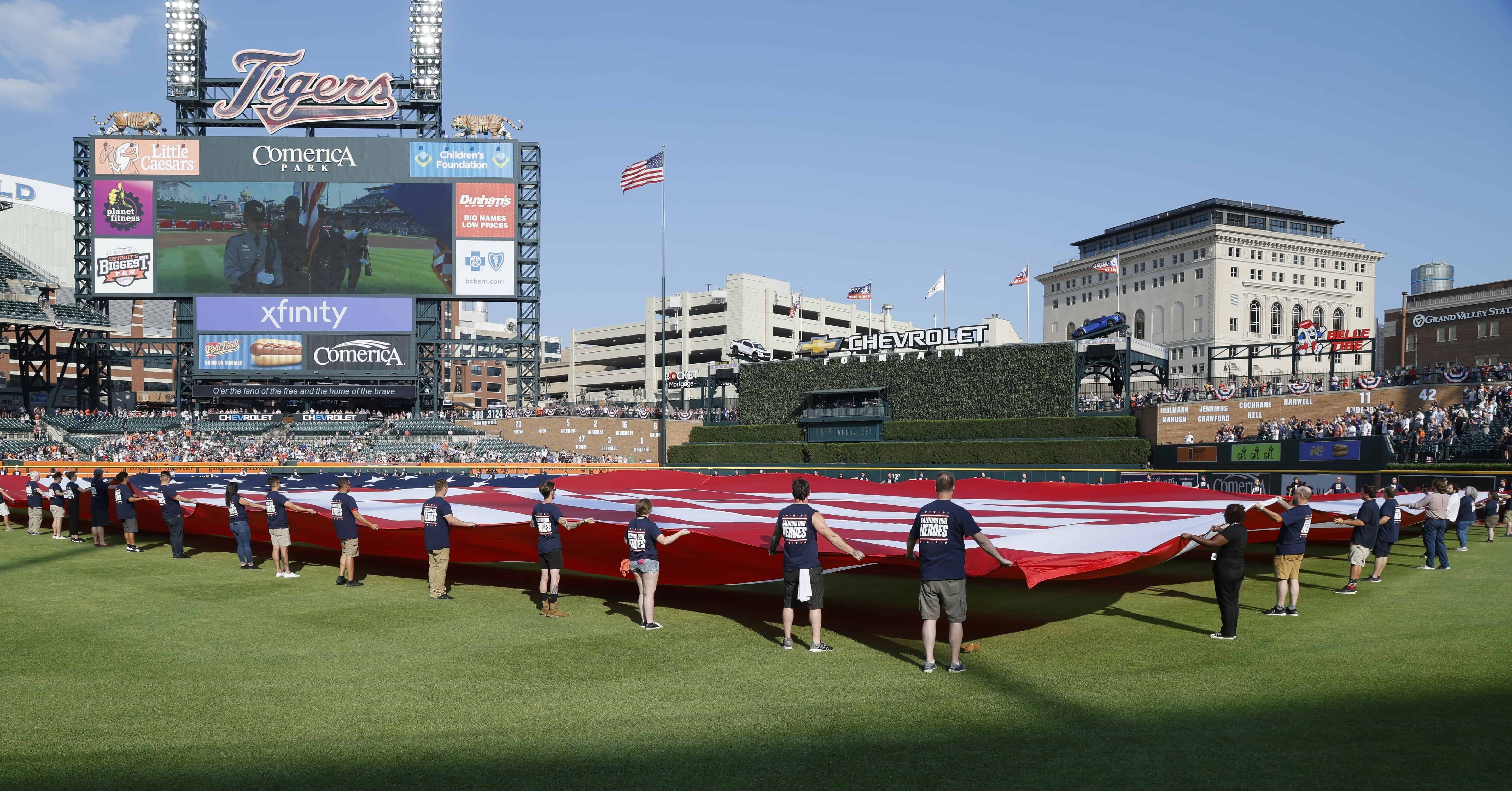 Una bandera de EE. UU. se despliega durante el himno nacional del partido de béisbol de los Tigres de Detroit contra los Atléticos de Oakland el Día de la Independencia, el martes 4 de julio de 2023, en Detroit.