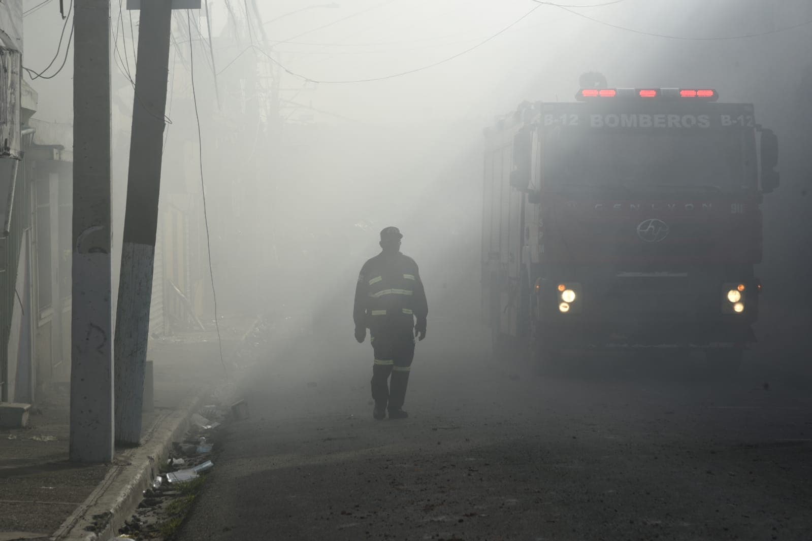Un bombero camina entre el humo que se desprende de los remanentes del incendio que se produjo tras la explosión en San Cristóbal.