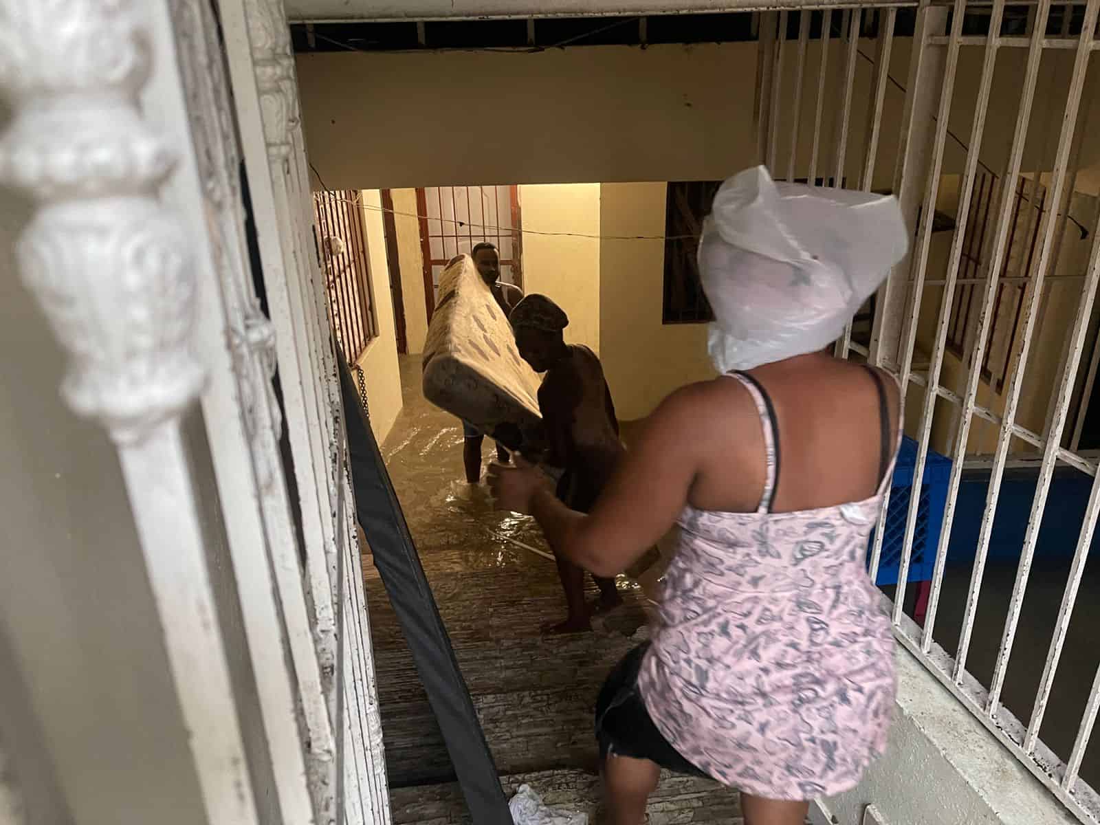 Vecinos de Las 800 se apresuran para sacar sus enseres de las viviendas afectadas por la crecida de la quebrada que pertenece al sector Los Ríos en Santo Domingo.