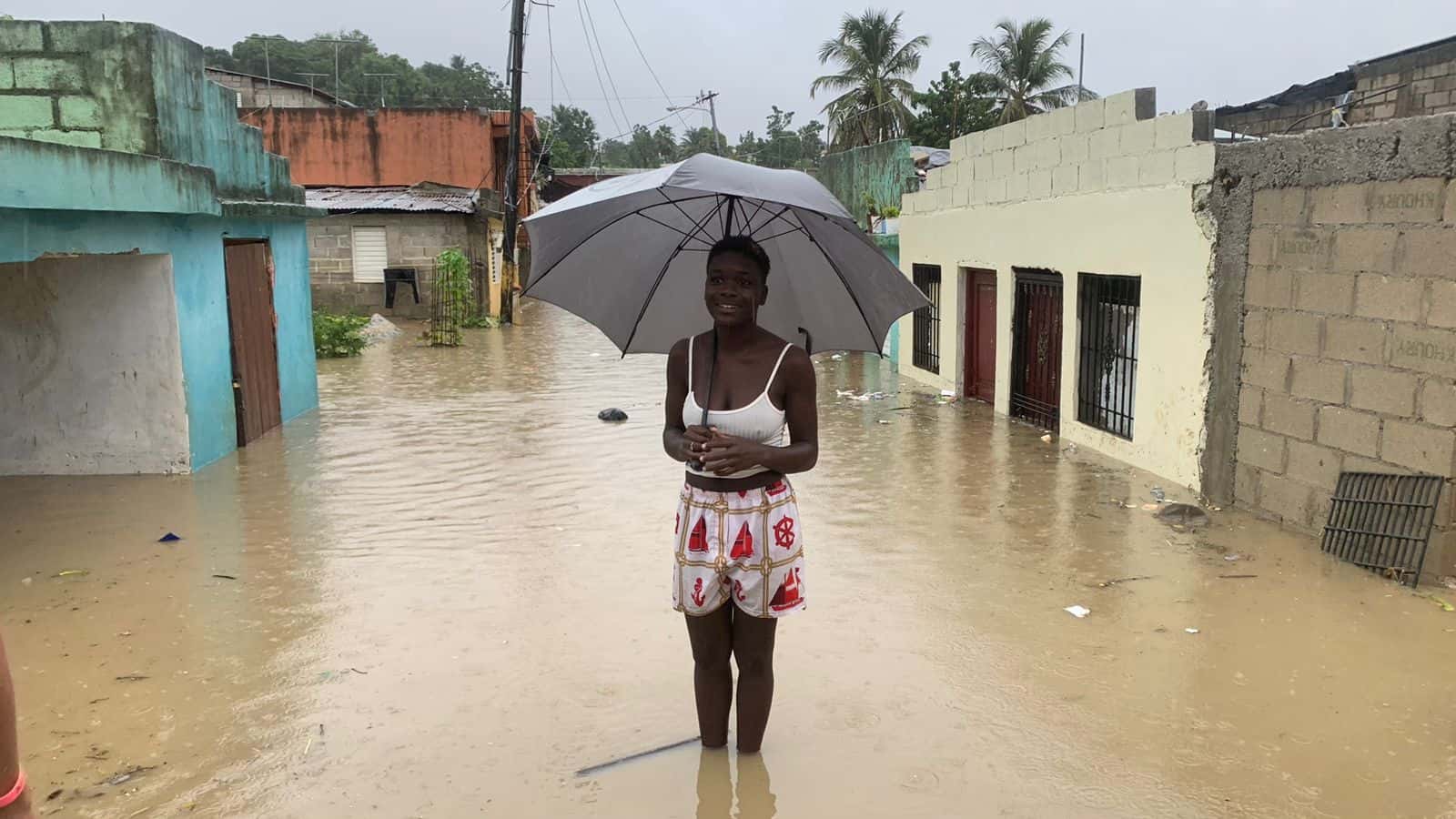 Una joven contempla el panorama de una calle inundada en el sector Manoguayano, en Santo Domingo Oeste.