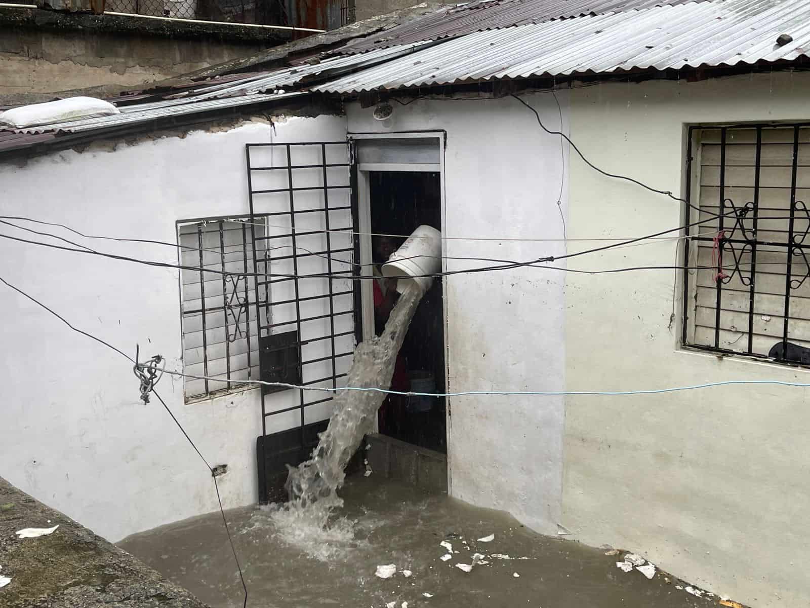 Habitantes del sector Juan Valdez de Villa Marina, en Santo Domingo Oeste, sacan agua de sus casas.