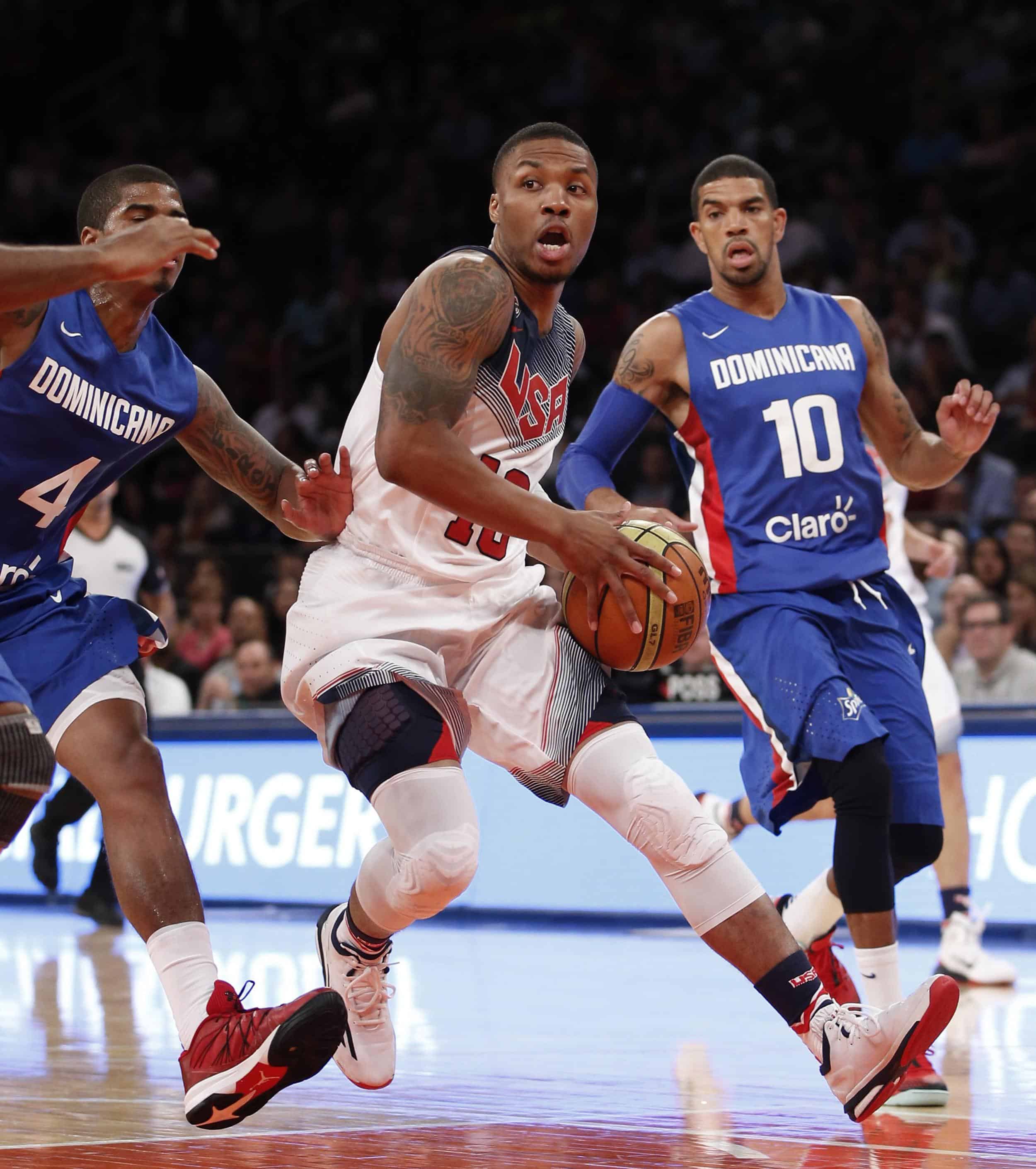 Edgar Sosa (i) y James Feldeine (d) defienden a Damian Lillard en un partido amistoso entre la República Dominicana y los Estados Unidos.