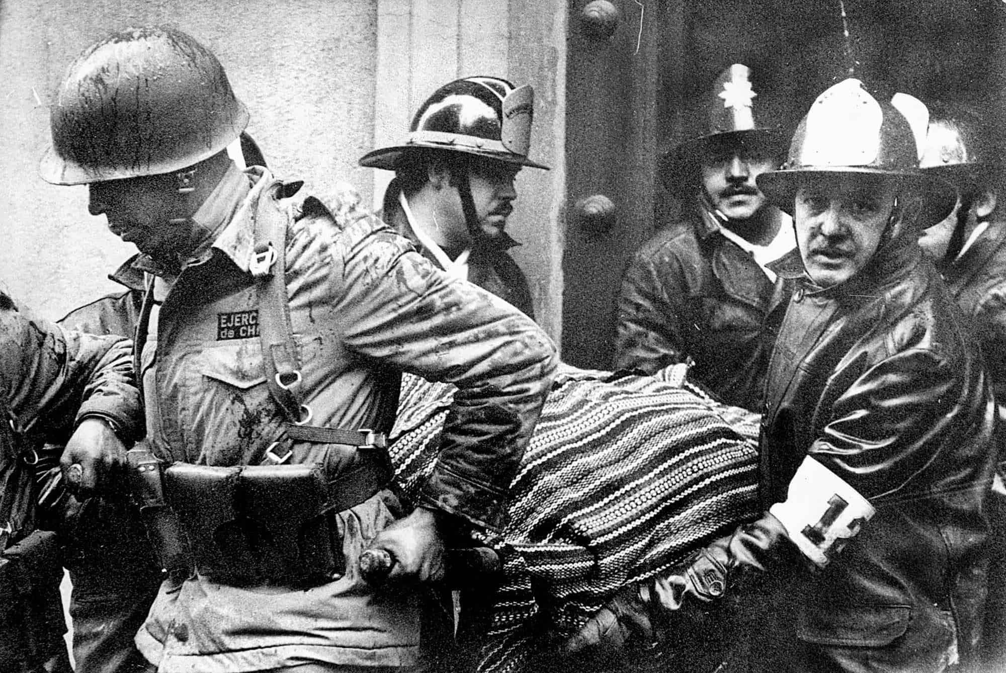 Soldados y bomberos sacan el cuerpo del presidente chileno Salvador Allende, envuelto en un poncho boliviano, fuera del palacio presidencial de La Moneda después de que fuera bombardeado durante un golpe de Estado del general Augusto Pinochet en Santiago, Chile, el 11 de septiembre de 1973.