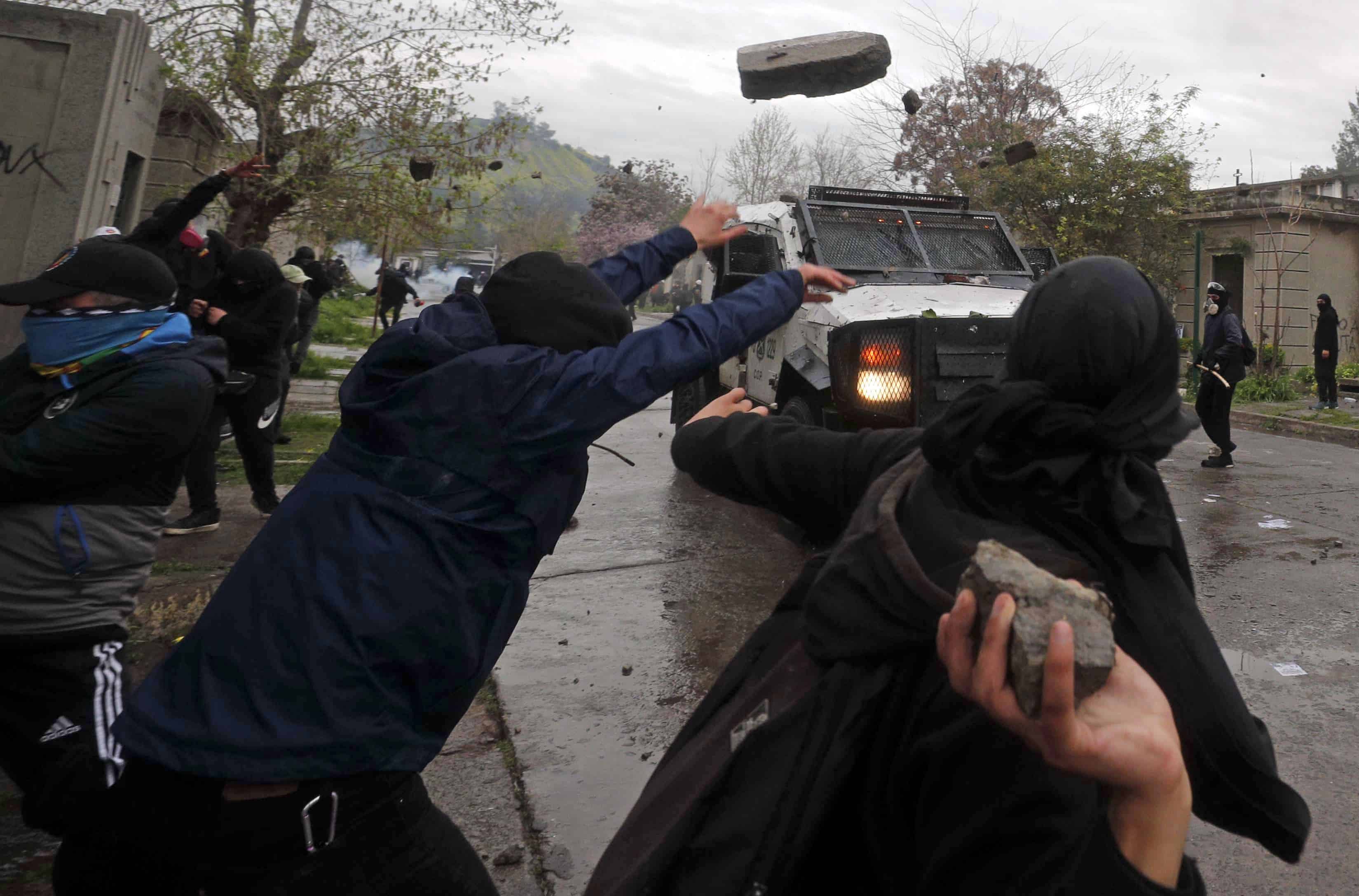 Manifestantes arrojan piedras contra un vehículo blindado de la policía durante enfrentamientos en una marcha que conmemora el 50 aniversario del golpe militar liderado por el general Augusto Pinochet en Santiago, Chile, el domingo 10 de septiembre de 2023.