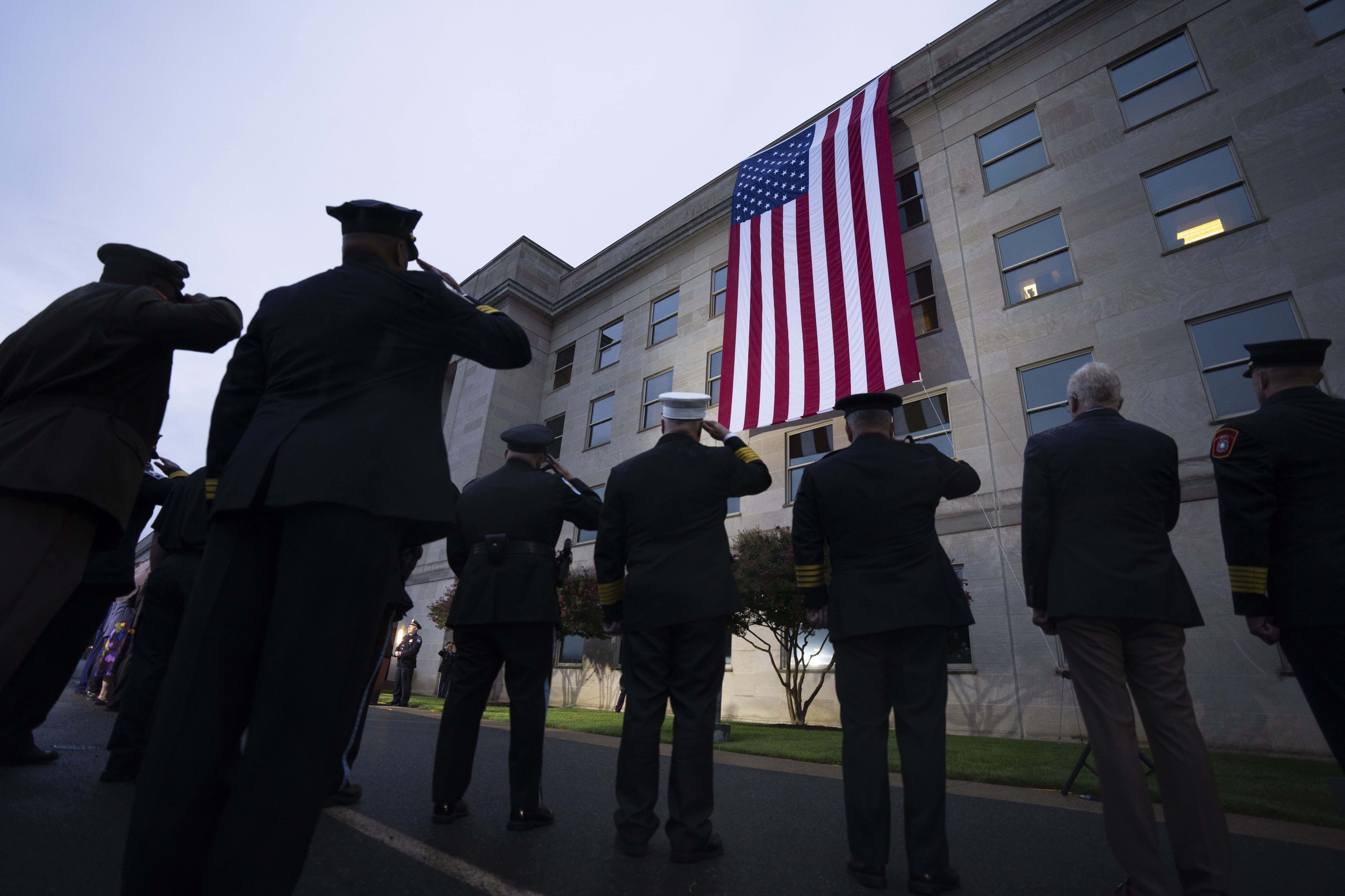 Los socorristas saludan mientras se despliega una bandera estadounidense en el Pentágono al amanecer para conmemorar el ataque terrorista de 2001 contra el Pentágono, durante una ceremonia de celebración, el lunes 11 de septiembre de 2023 por la mañana en Washington.