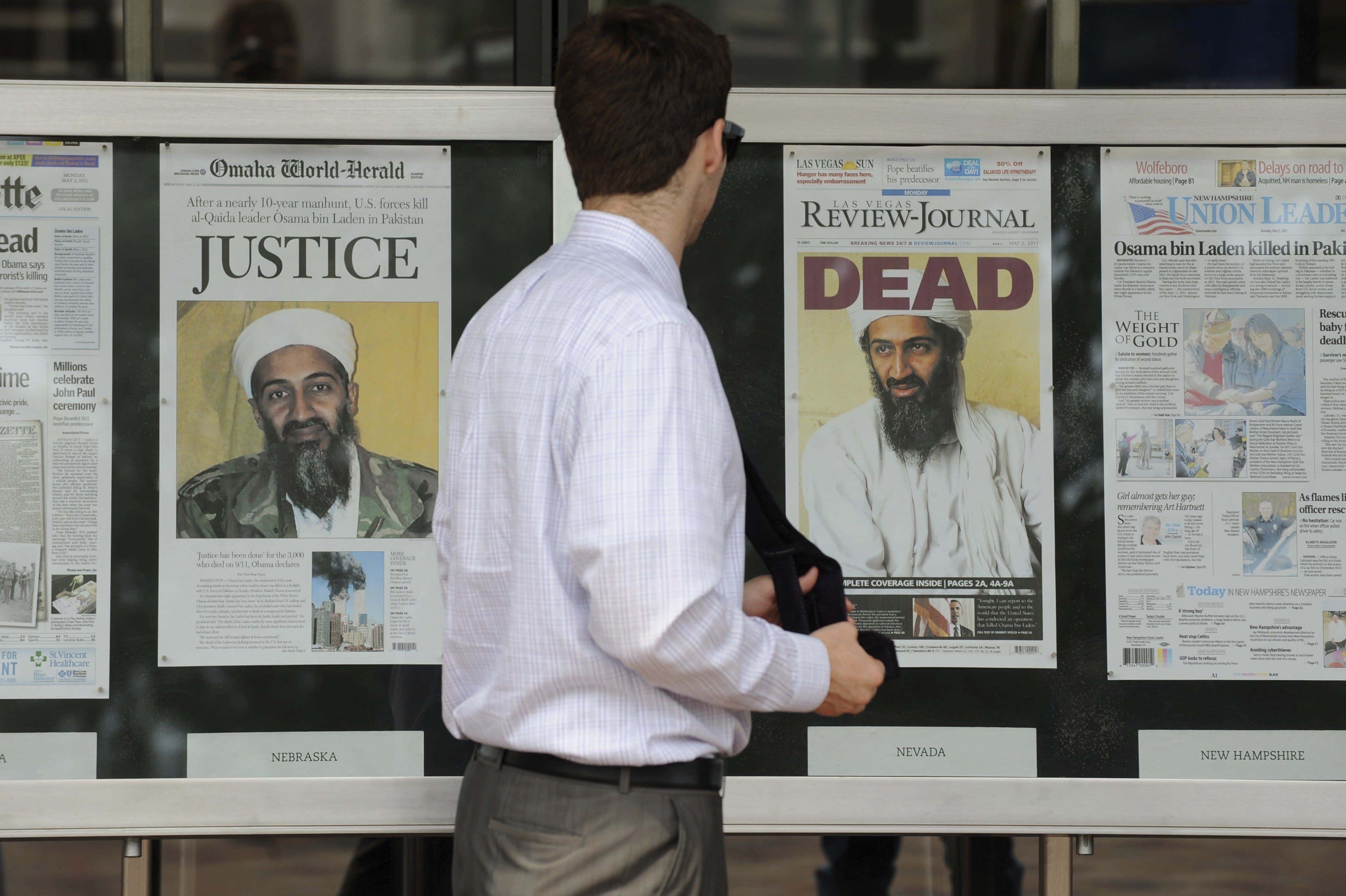 Un hombre pasa ante las portadas de varios periódicos estadounidenses que muestran imágenes de Osama bin Laden en el exterior del Newseum, en Washington (EEUU),  el lunes 2 de mayo de 2011.