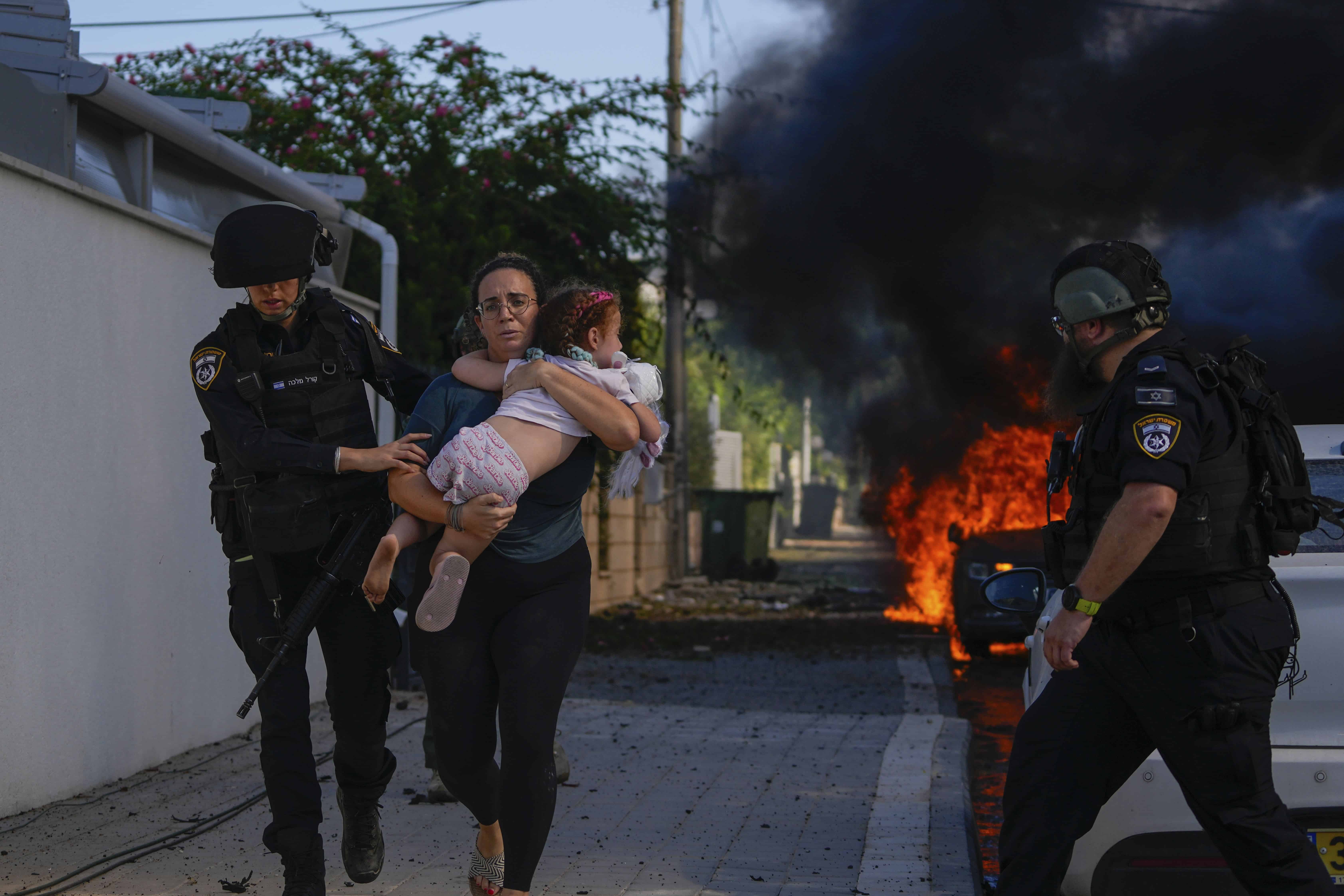 Agentes de policía evacuan a una mujer y un niño de un lugar alcanzado por un cohete disparado desde la Franja de Gaza, en Ashkelon, sur de Israel, el sábado 7 de octubre de 2023. Los cohetes se dispararon cuando Hamás anunció una nueva operación contra Israel.