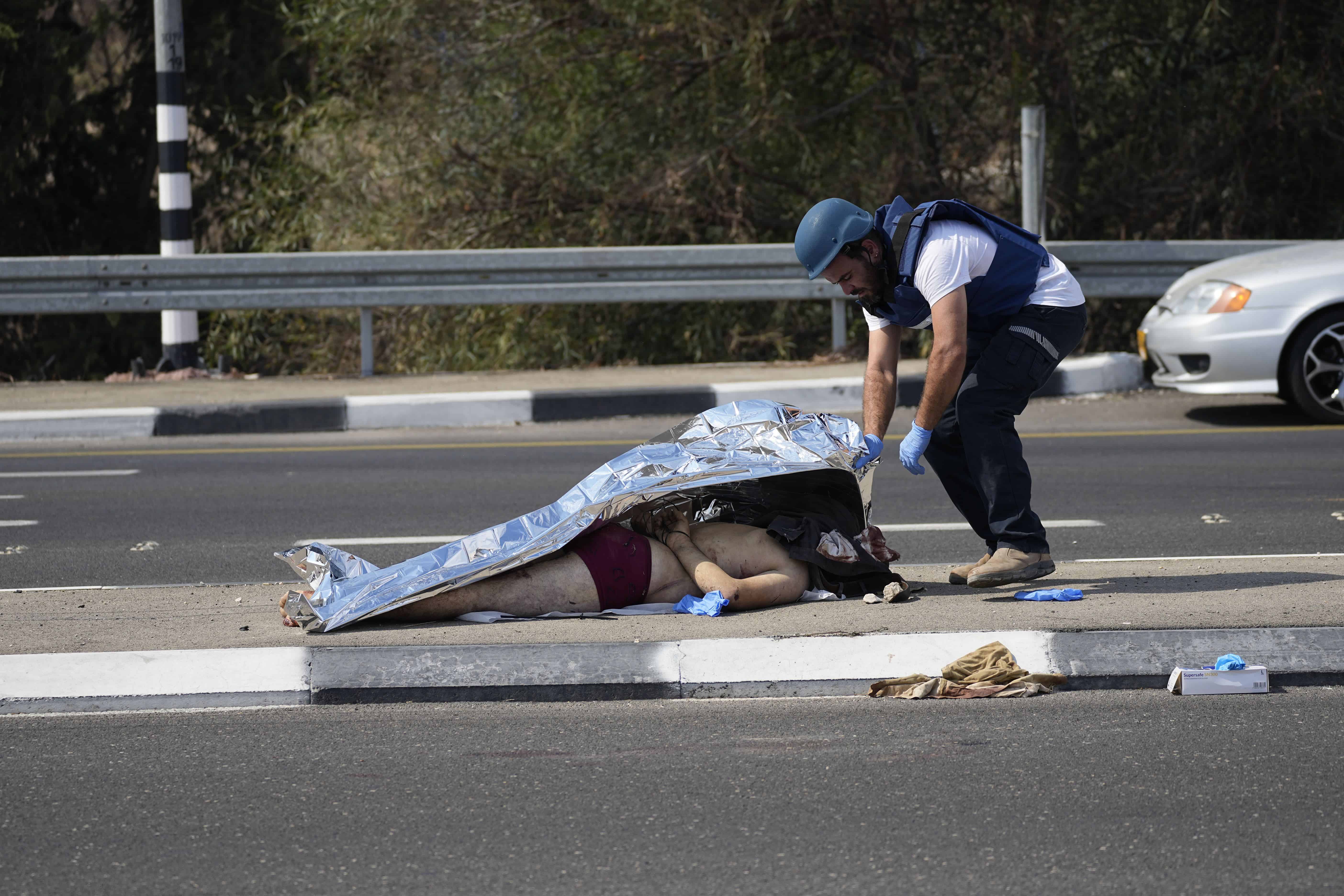 Un policía israelí cubre a un militante palestino asesinado cerca de la Franja de Gaza en las afueras de Ashkelon, Israel, el sábado 7 de octubre de 2023.