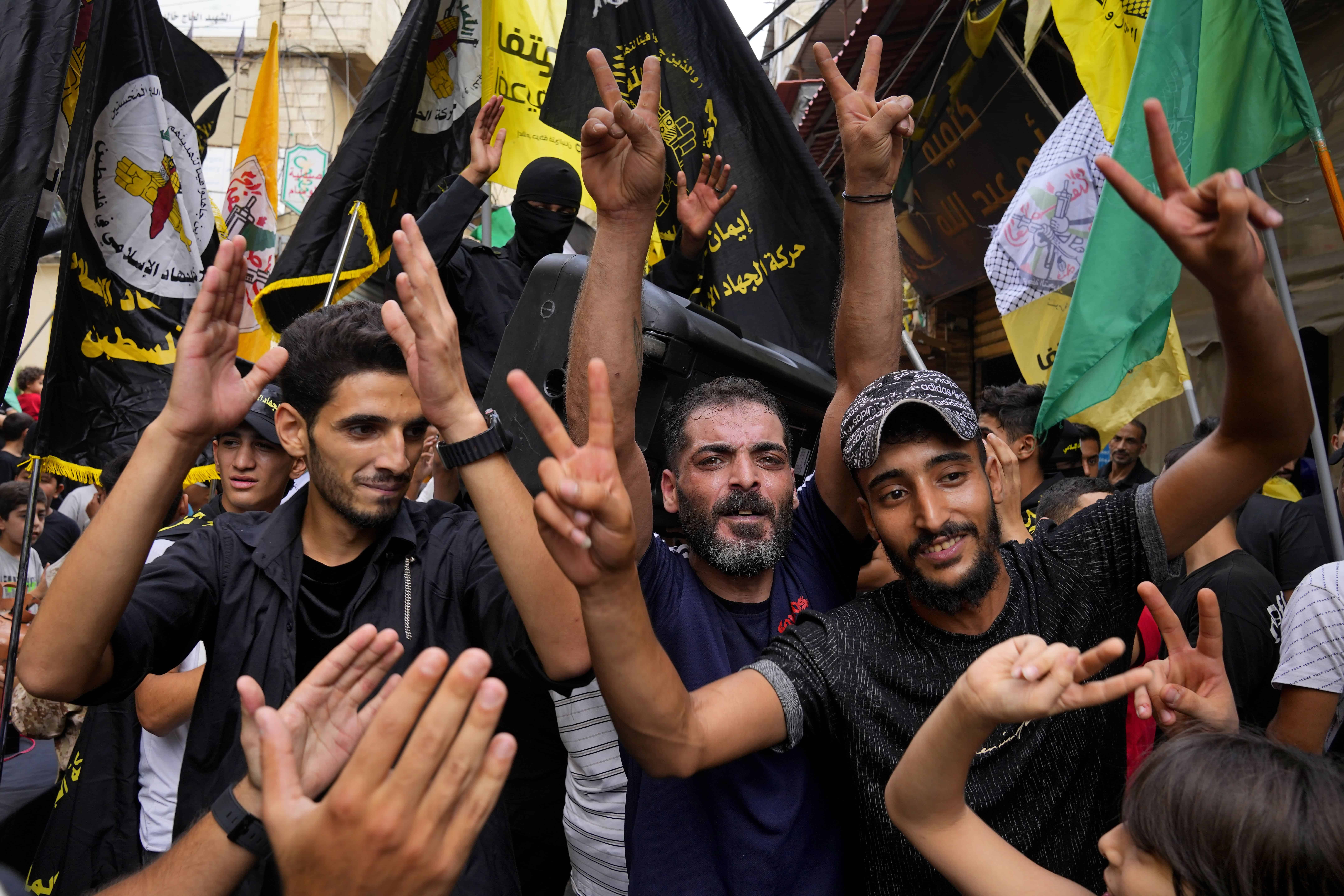 La gente hace el signo de la victoria para celebrar los ataques que el grupo militante Hamás llevó a cabo contra Israel, en el campo de refugiados palestinos de Bourj al-Barajneh, en Beirut, Líbano, el sábado 7 de octubre de 2023.