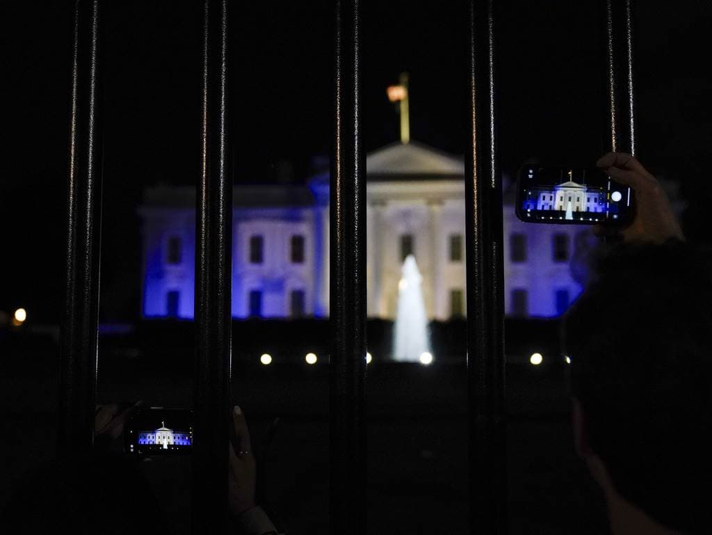 Una persona fotografía la Casa Blanca desde la avenida Pensilvania, iluminada de azul y blanco para subrayar la solidaridad de Estados Unidos con Israel, el lunes 9 de octubre de 2023, en Washington.