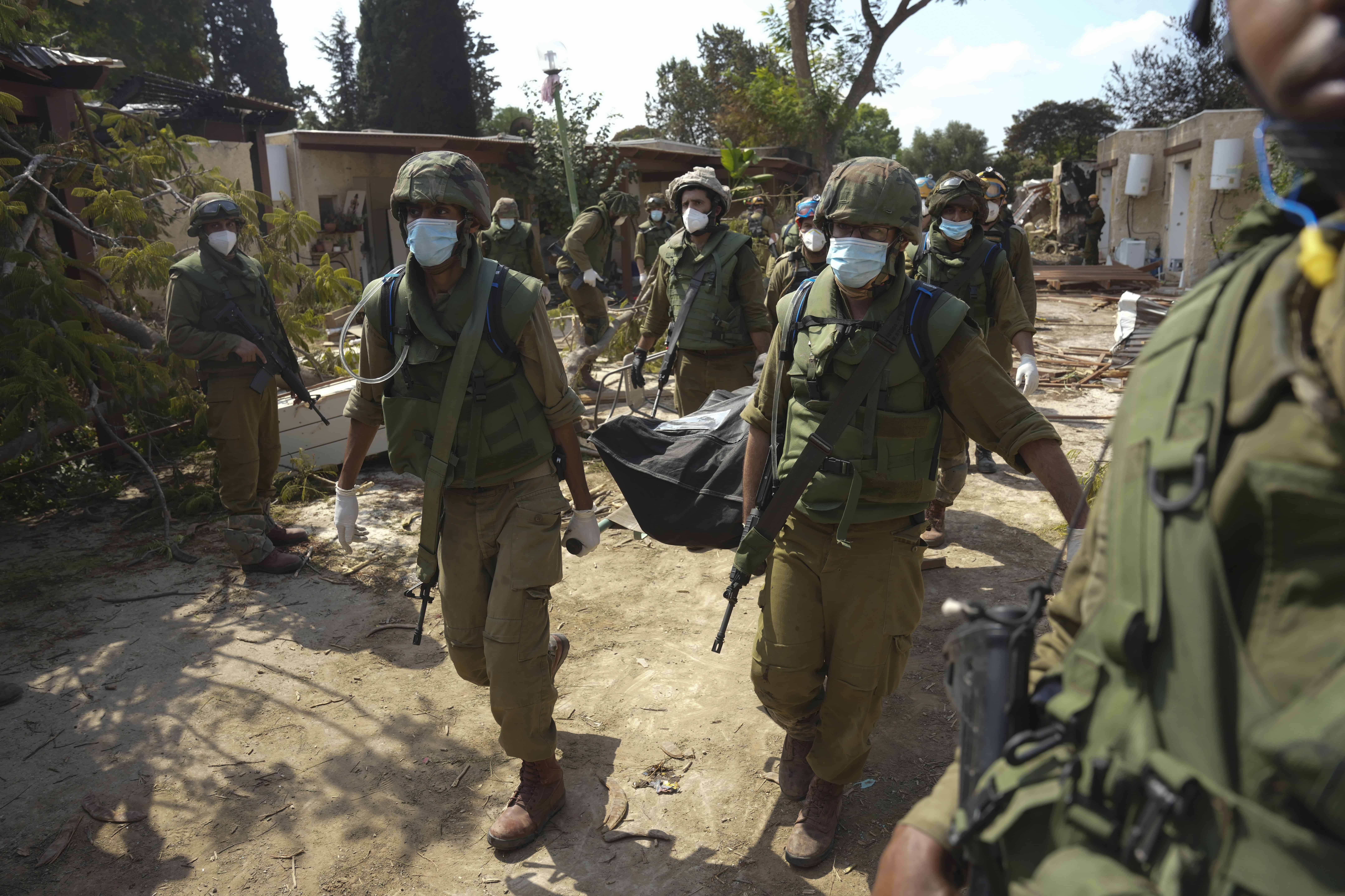 Soldados israelíes cargan el cuerpo de una persona que murió en un ataque de Hamas, el martes 10 de octubre de 2023, en el kibbutz Kfar Aza. Combatientes de Hamas incursionaron el sábado en el kibbutz, donde mataron y secuestraron a varios israelíes.