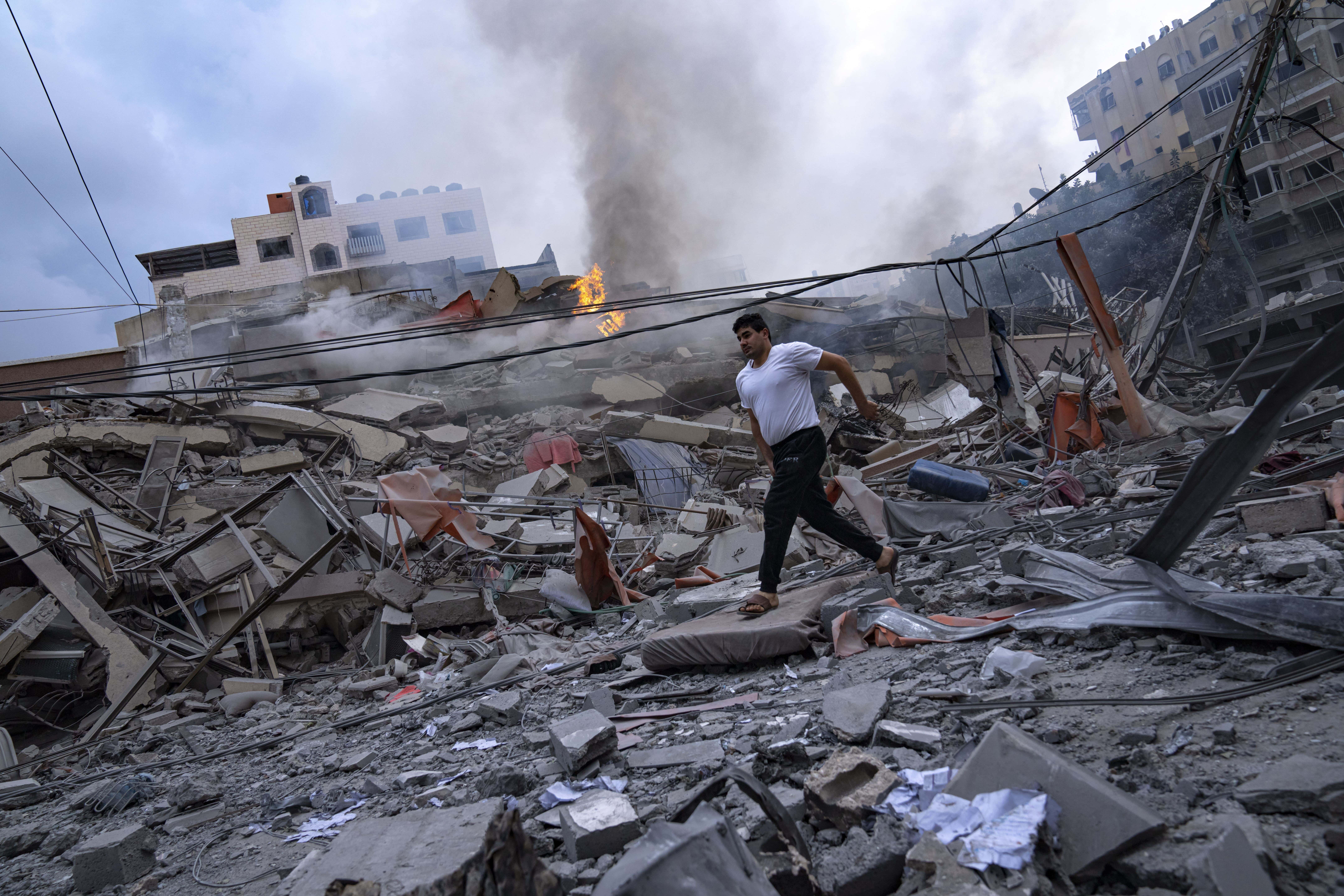 Palestinos caminan entre los escombros que dejaron los ataques israelíes contra algunas zonas de un vecindario en la Ciudad de Gaza, el martes 10 de octubre de 2023. Hamas, el grupo islamista que gobierna la Franja de Gaza, llevó a cabo el sábado un ataque sin precedentes contra Israel, dejando más de 1,000 muertos y varios secuestrados.