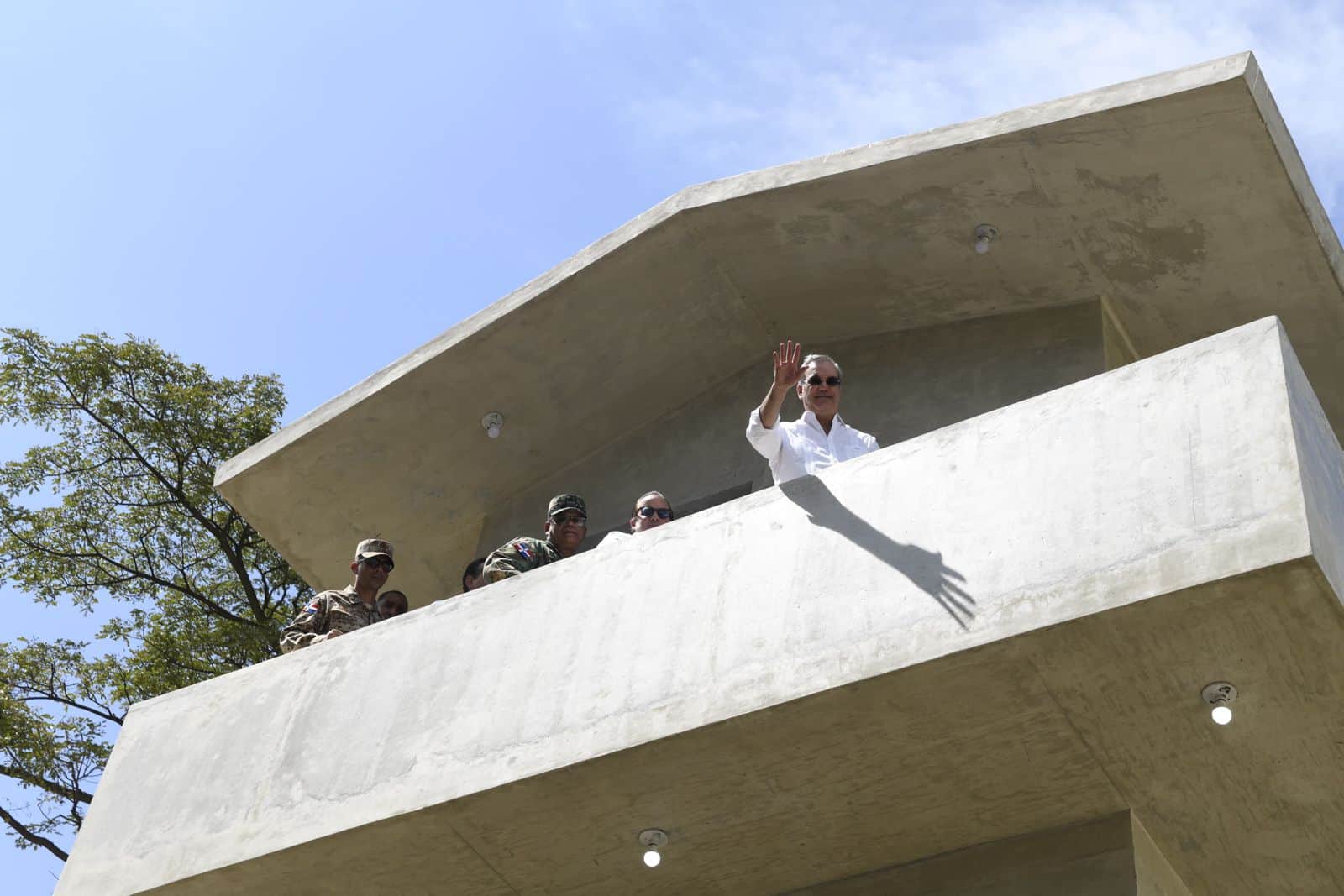 El presidente Luis Abinader saluda desde una torre de vigilancia en la verja perimetral de Elías Piña.