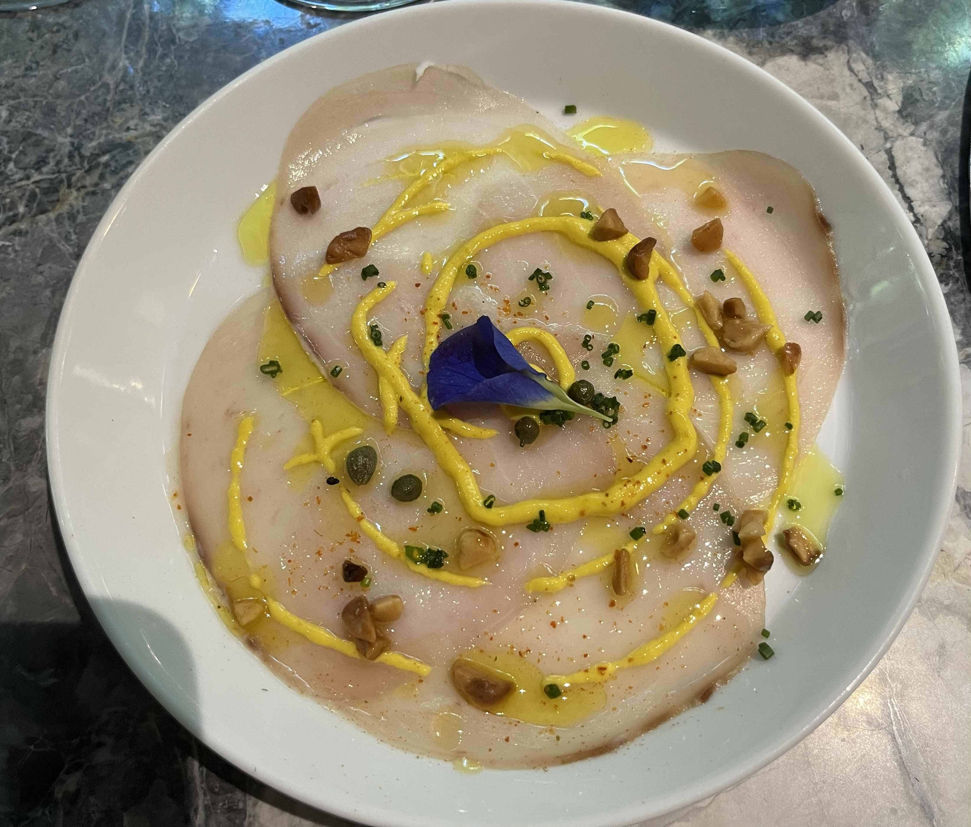 Pez espada en crema de ajíes dulces con aceite de aguacate y macadamia tostada.