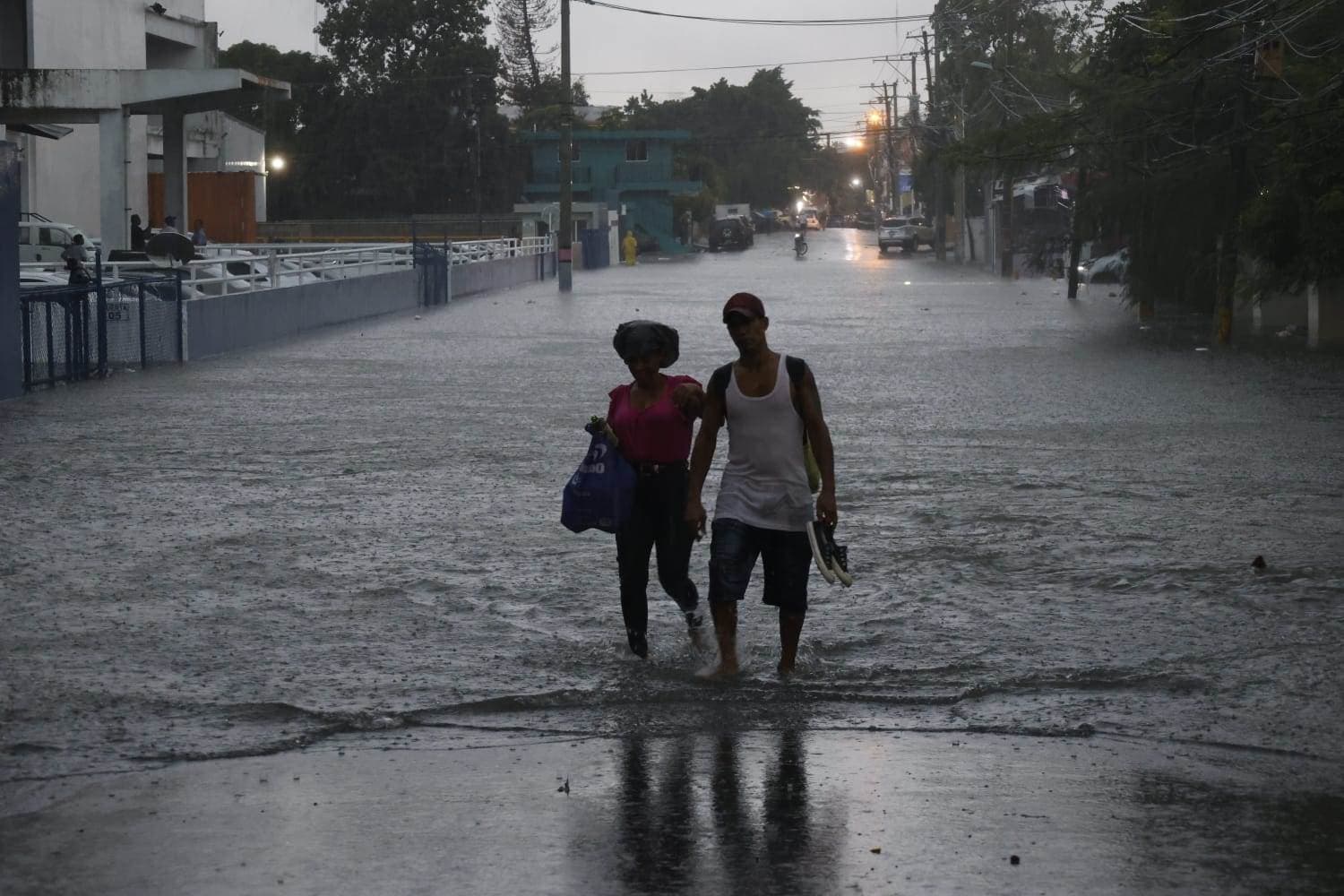 Tomados de la mano una pareja cruzó una calle inundada en el sector Los Prados.