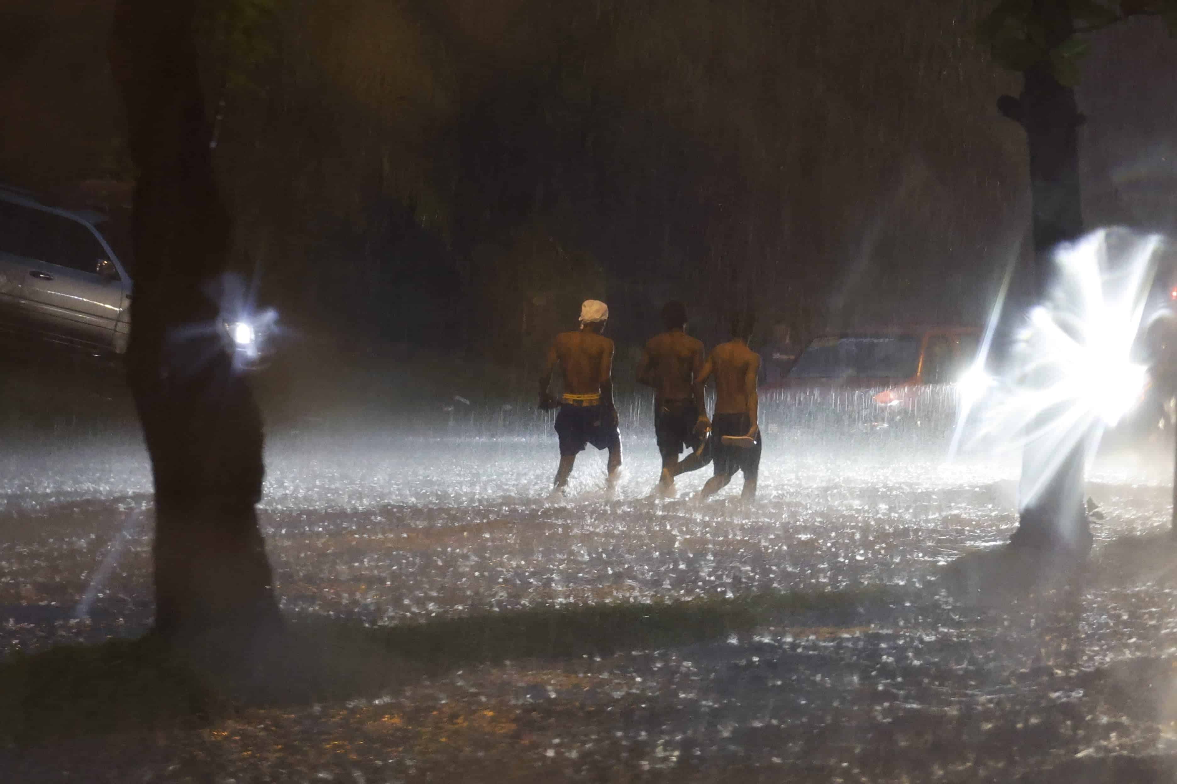 Tres jóvenes cruzaron la avenida de los Próceres con el torso descubierto en medio de la tormenta que azotó Santo Domingo.