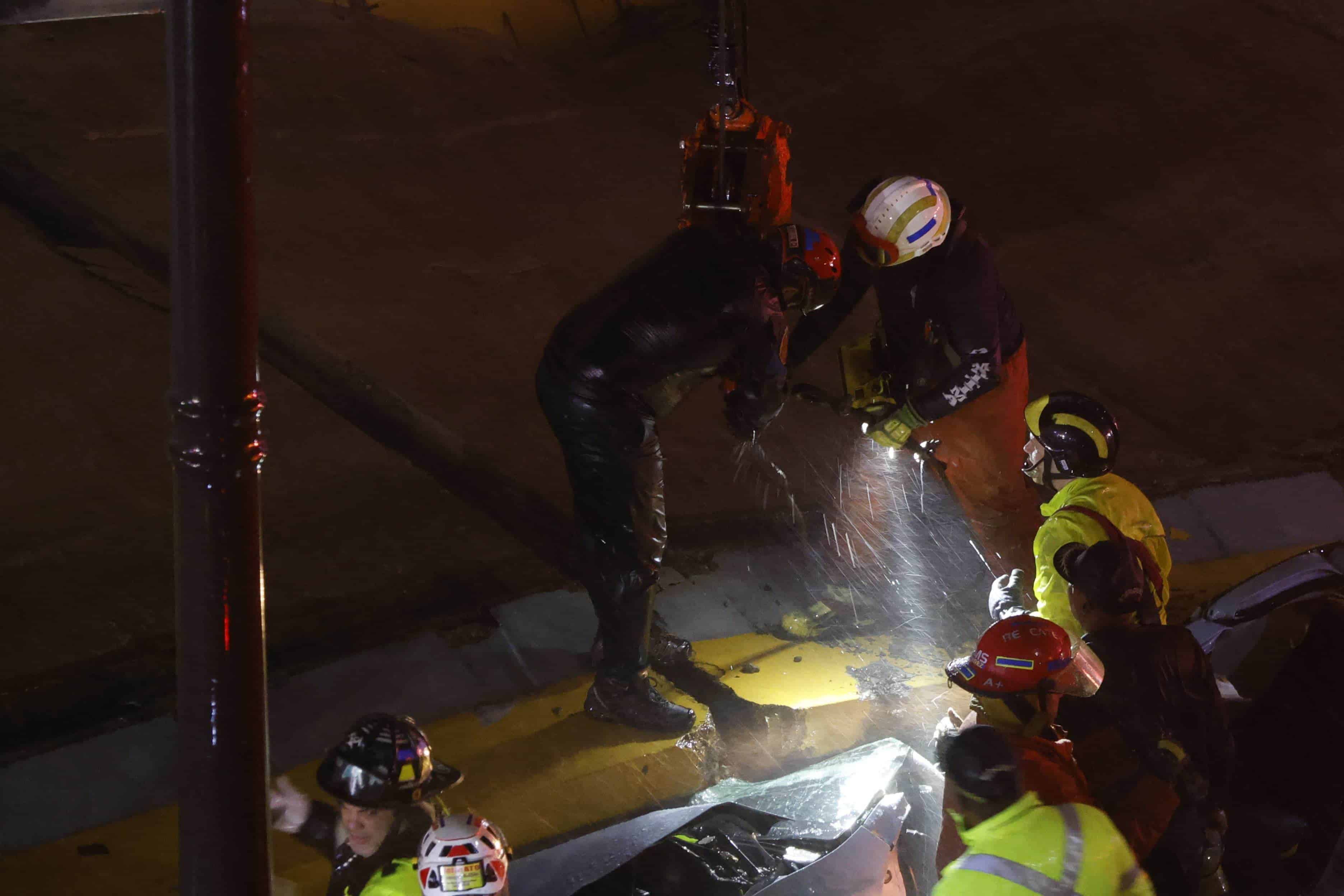 Trabajadores del MOPC se auxilian de una grúa para liberar a las personas atrapadas en el colapso de una pared en el paso a desnivel de la avenida 27 de Febrero.