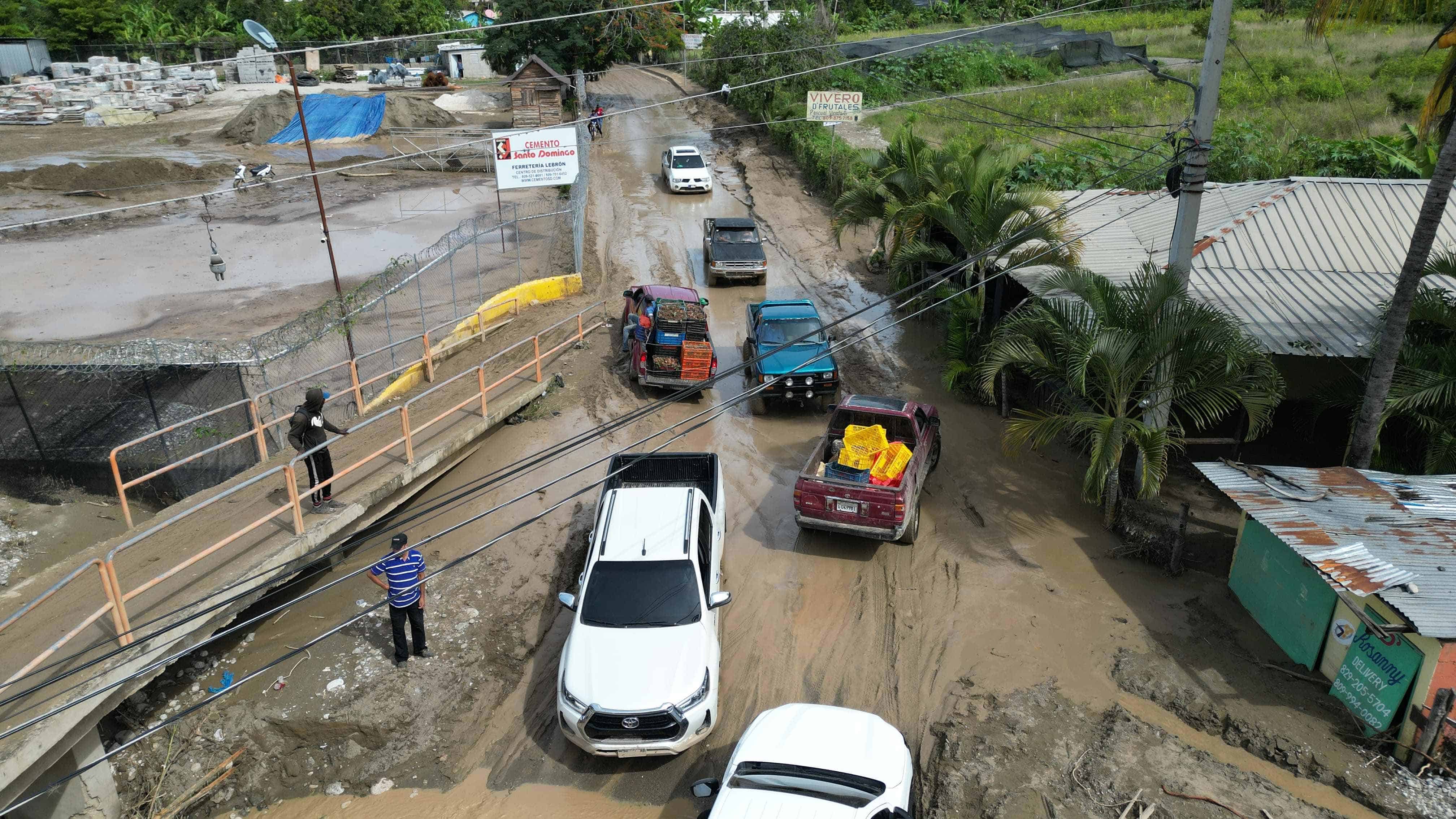 Personas intentan pasar el cruce del arroyo Lima en Los Indios de Padre Las Casas, Azua.