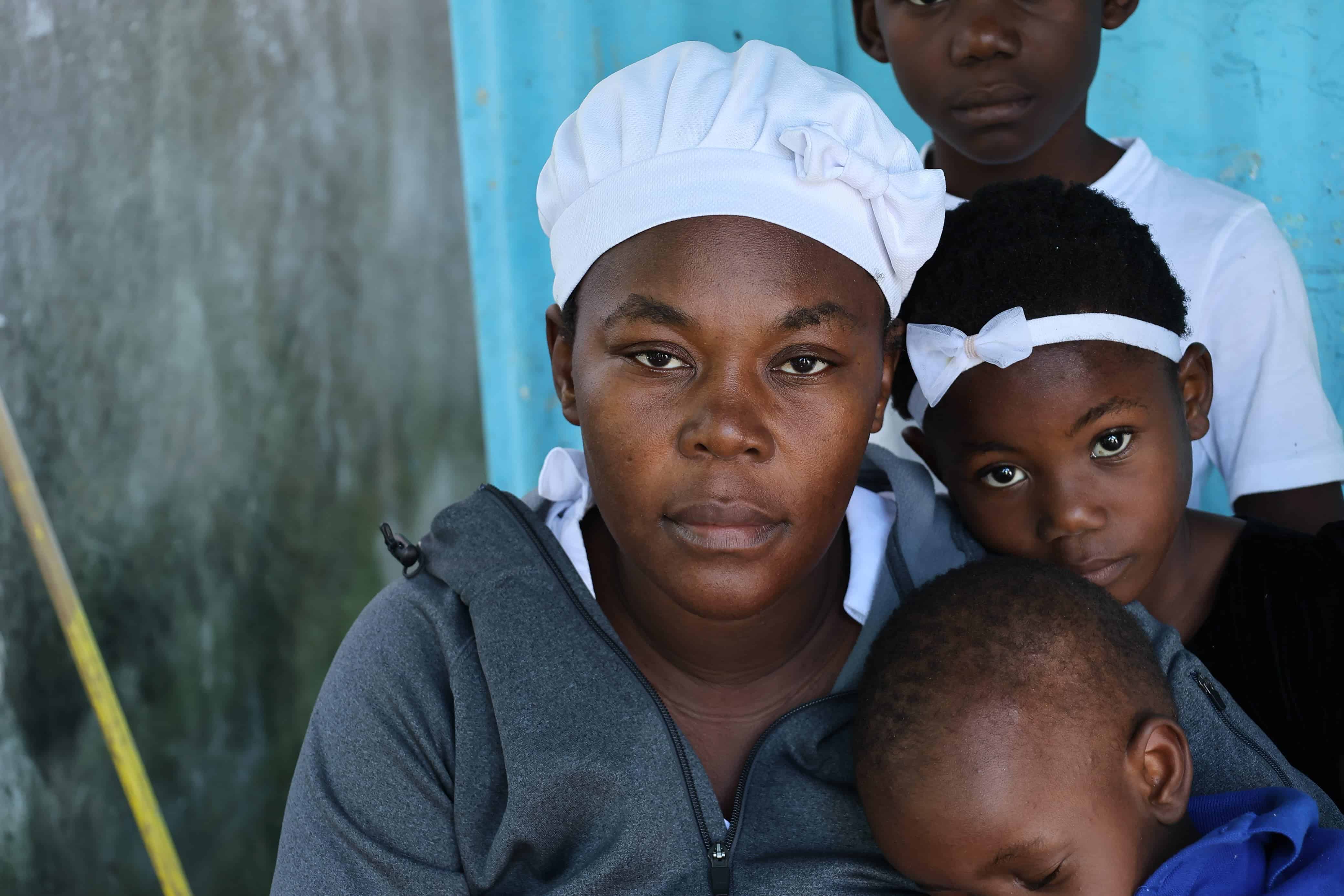 La esposa de Bonheur Donvelier, una de las víctimas del colapso de la estructura del paso a desnivel de la 27 de febrero,  junto a sus hijos en una comunidad de Baní.