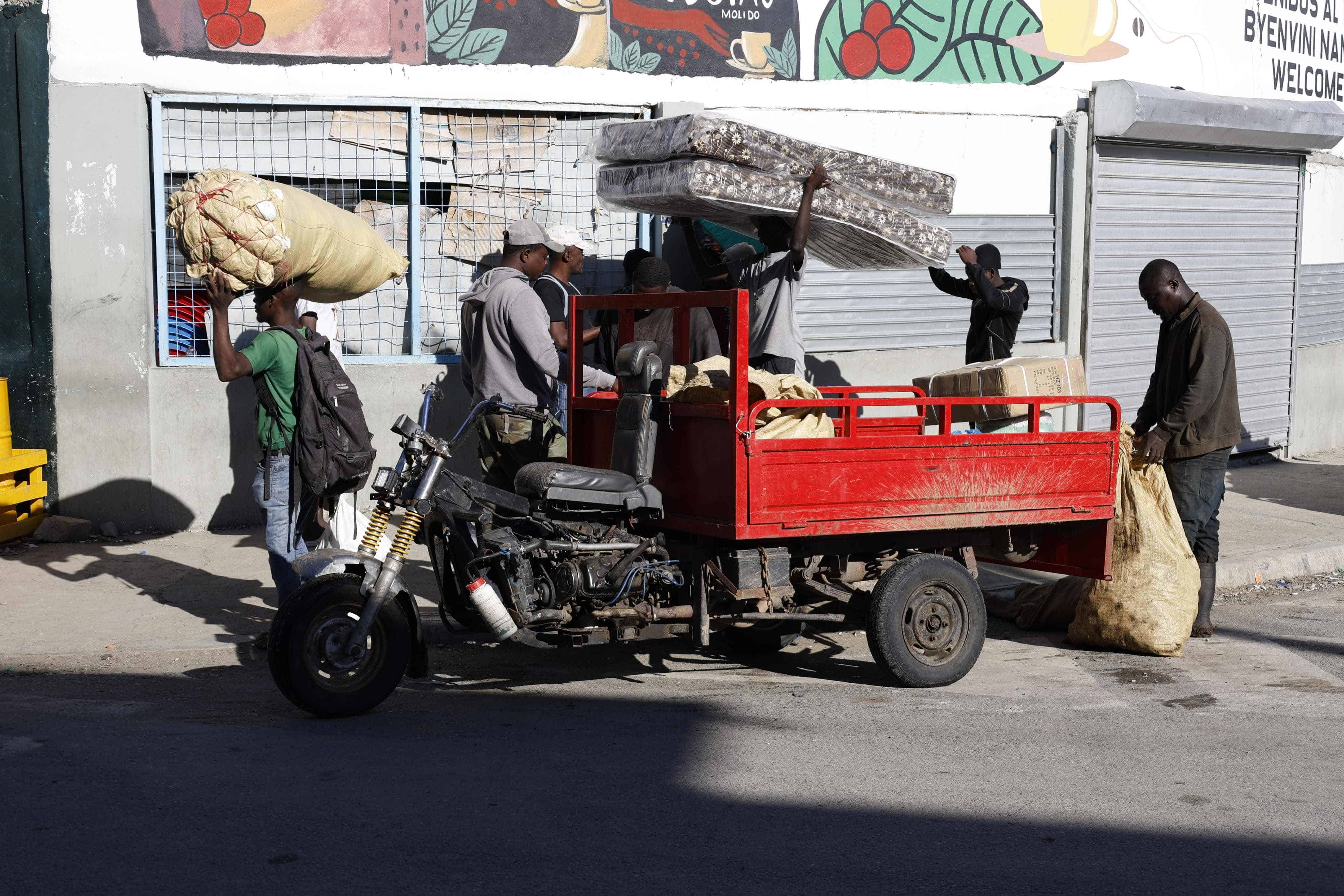 Los haitianos cargan a pie los objetos o productos que escasean en su territorio. 