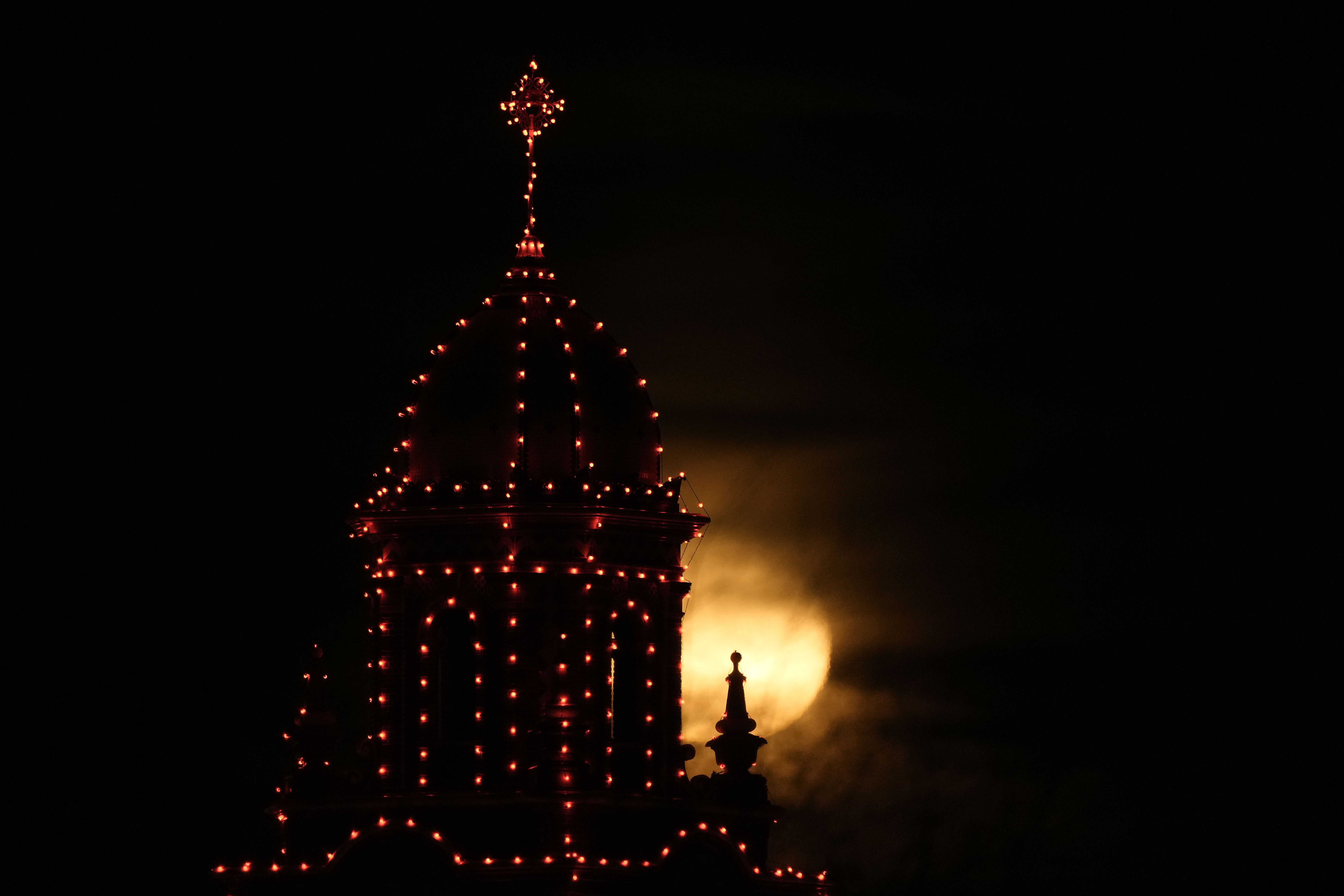 La luna sale más allá de una torre delineada con luces navideñas en el centro comercial Country Club Plaza, el miércoles 29 de noviembre de 2023, en Kansas City, Missouri