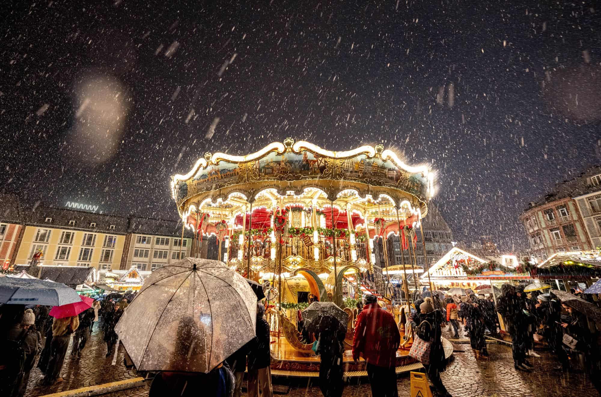 La nieve cae cuando se inauguró el tradicional mercado navideño con el tiovivo en Frankfurt, Alemania, el lunes 27 de noviembre de 2023.
