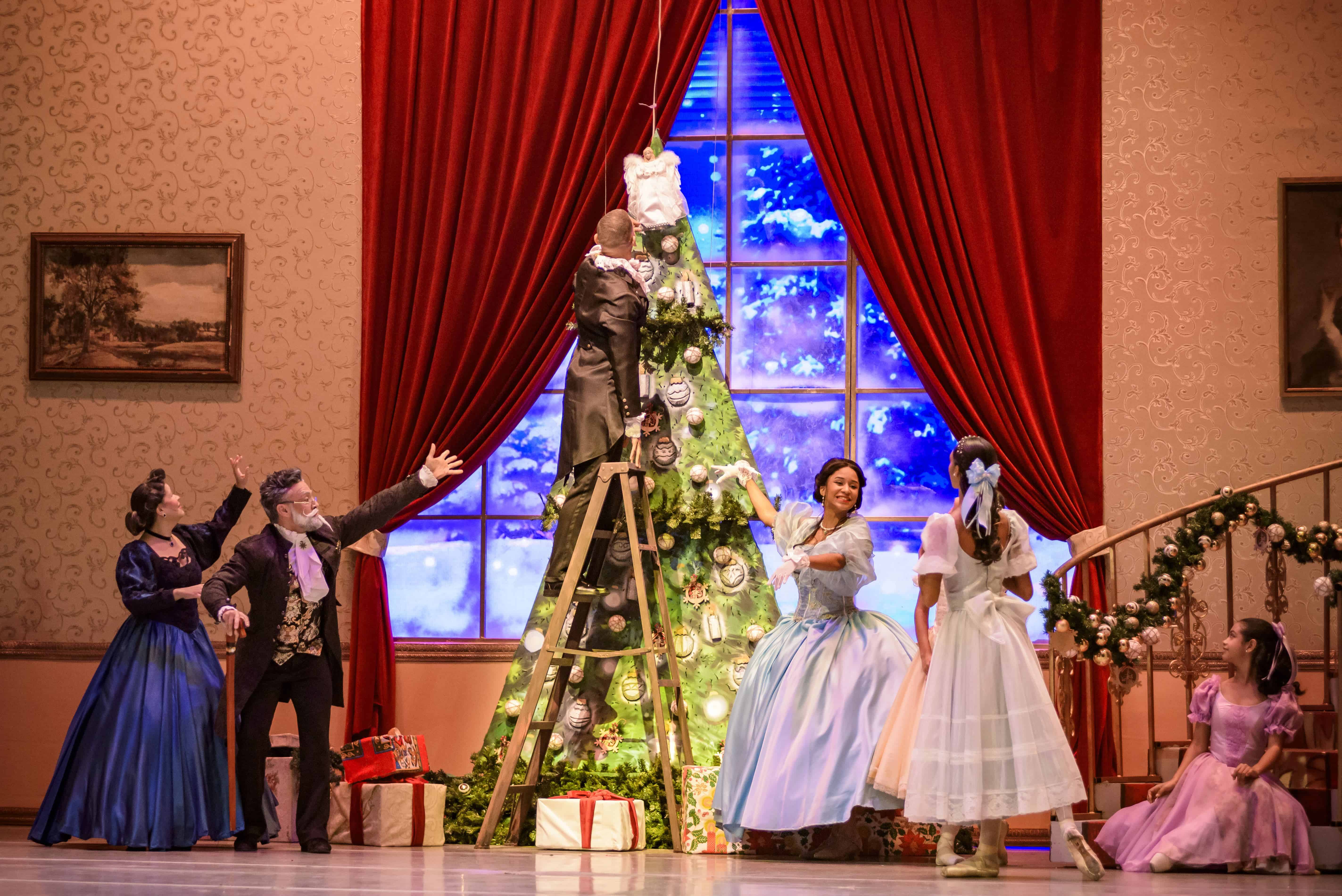 La familia se acerca para ver cuando colocan el Ángel de la navidad al árbolito.