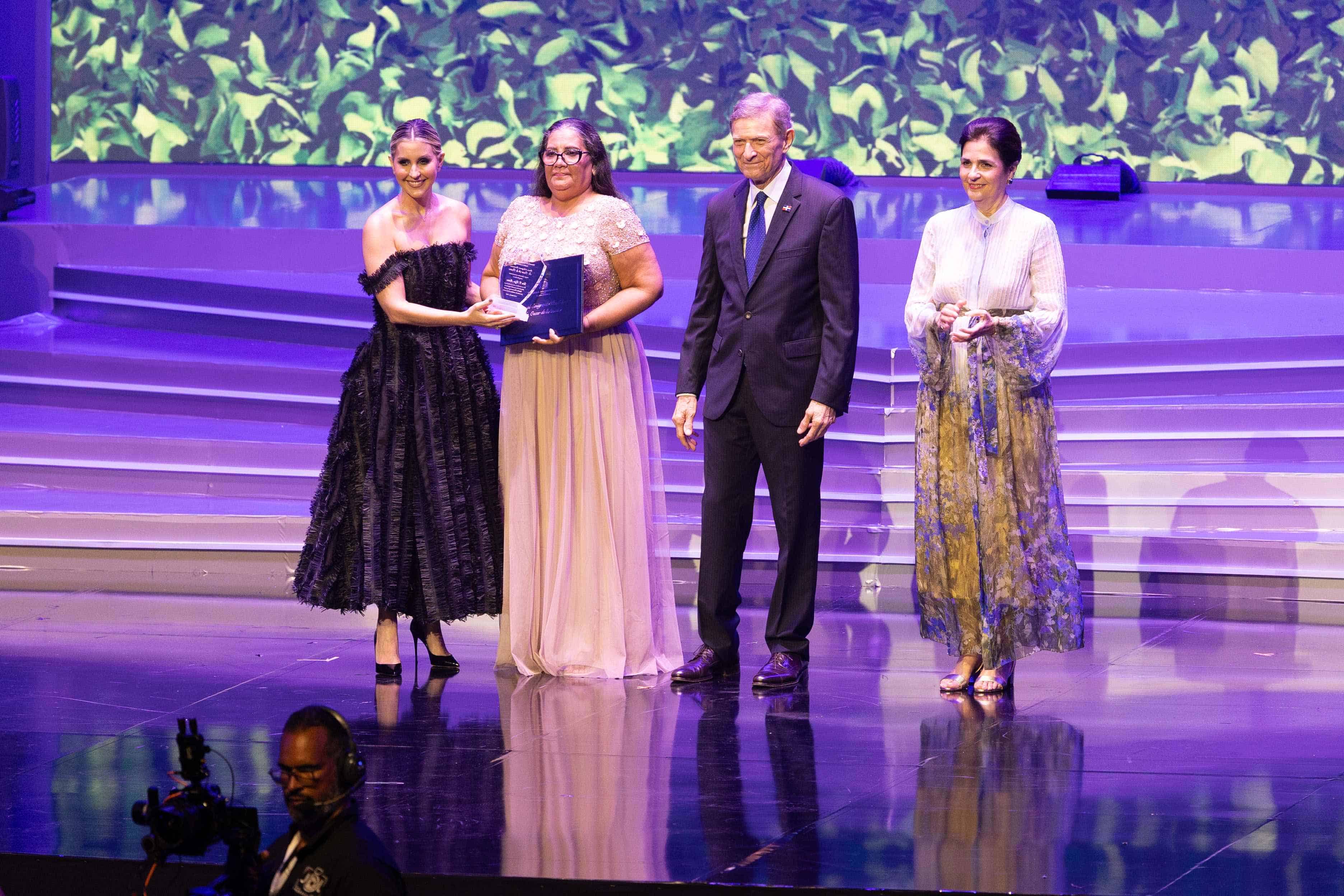 Iris Violeta Rijo recibe el reconocimiento de la mano de Alejandra Castillo, Roberto Álvarez y María Amalia León.