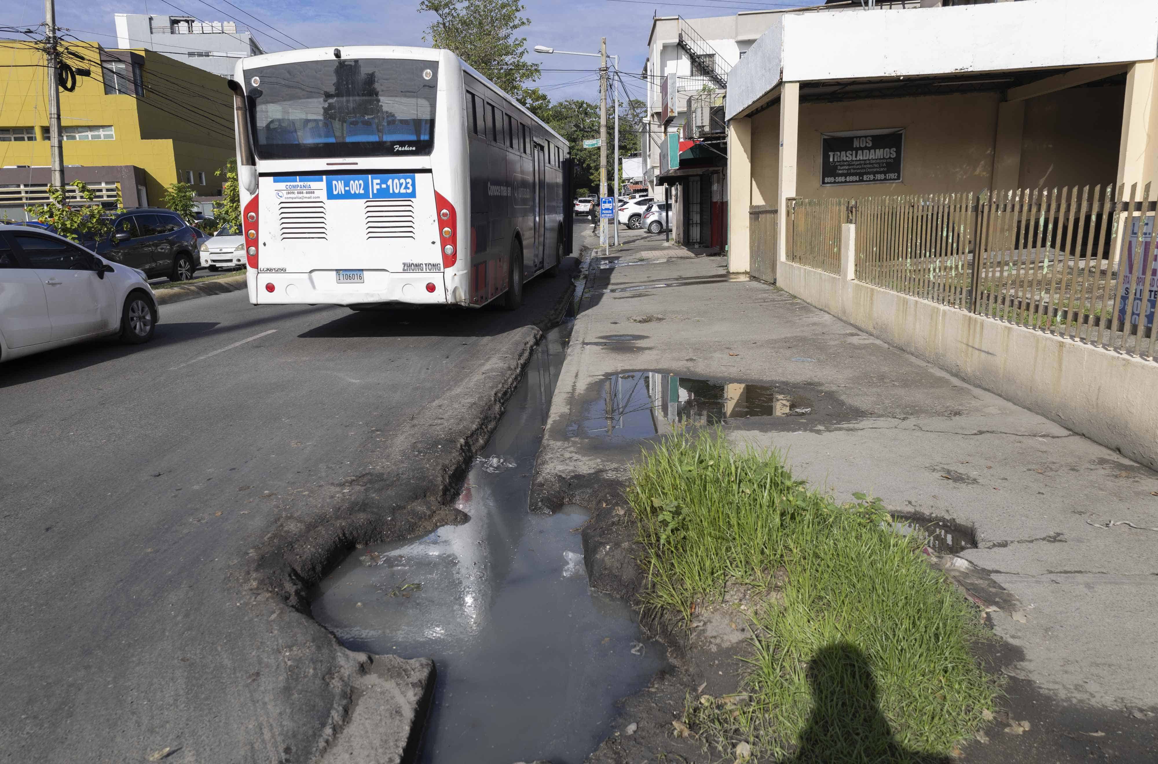 Pasajeros esperan autobuses en el mismo lugar del brote de aguas sanitarias.