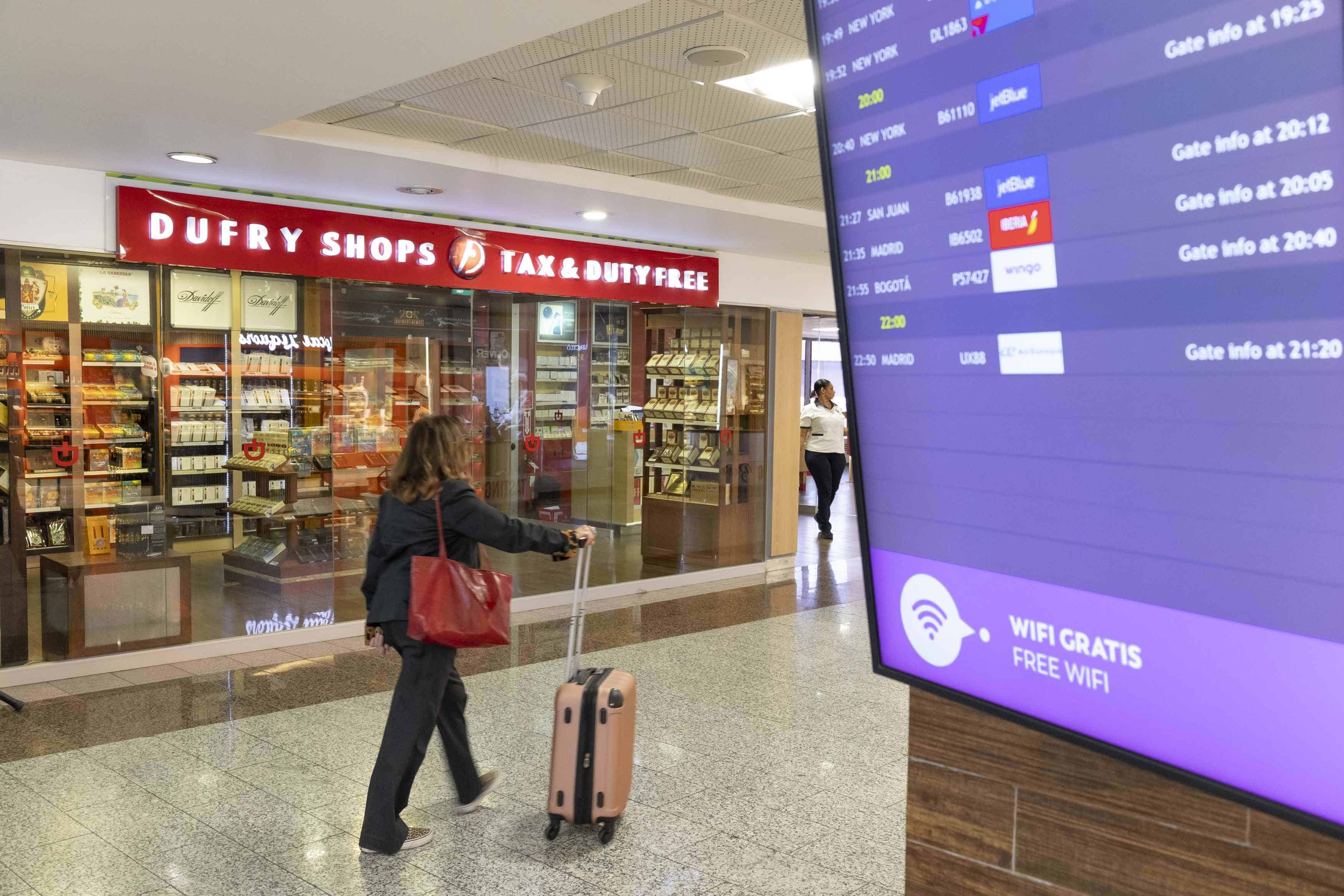 Una pasajera en la zona restreingida de la terminal B del aeropuerto, donde se visualiza una pantalla con los itinerarios de vuelo.