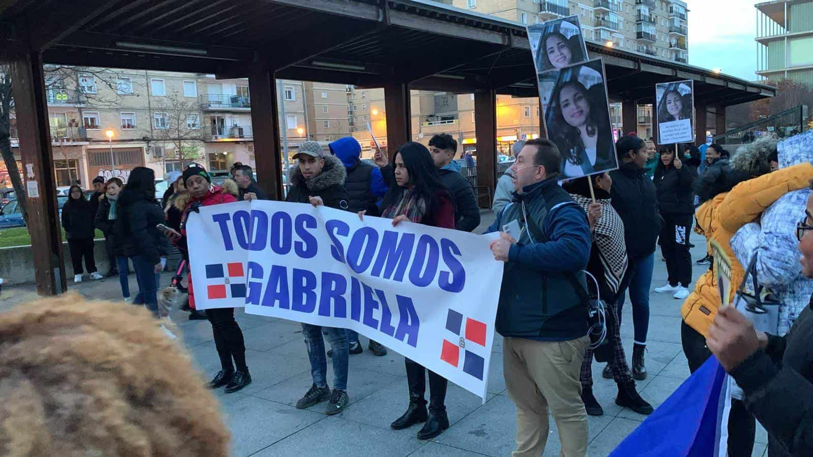 Mariel Reyes sostiene un cartel que reza Todos somos Gabriela en medio de dos banderas dominicanas durante la concentración de este miércoles. 