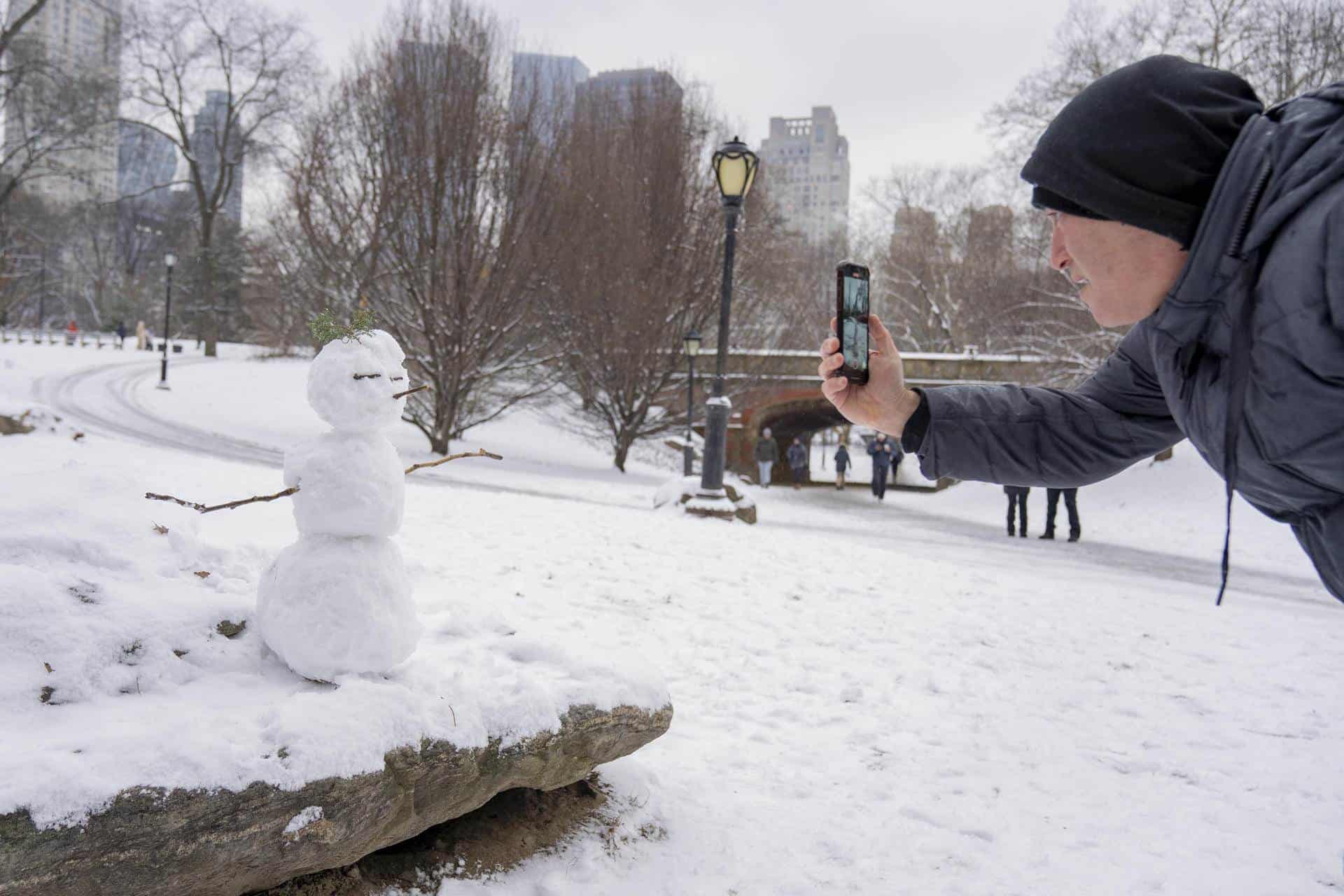 Una persona toma una fotografía a un muñeco de nieve tras la primera nevada de 2024 hoy, en Central Park en Nueva York (EE.UU.).