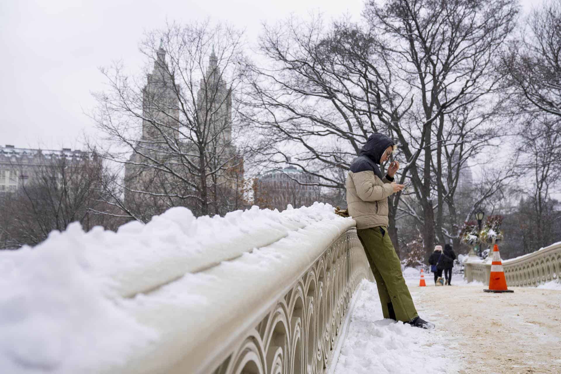 Una persona revisa su teléfono sobre un puente tras la primera nevada de 2024 hoy, en Central Park en Nueva York (EE.UU.). 