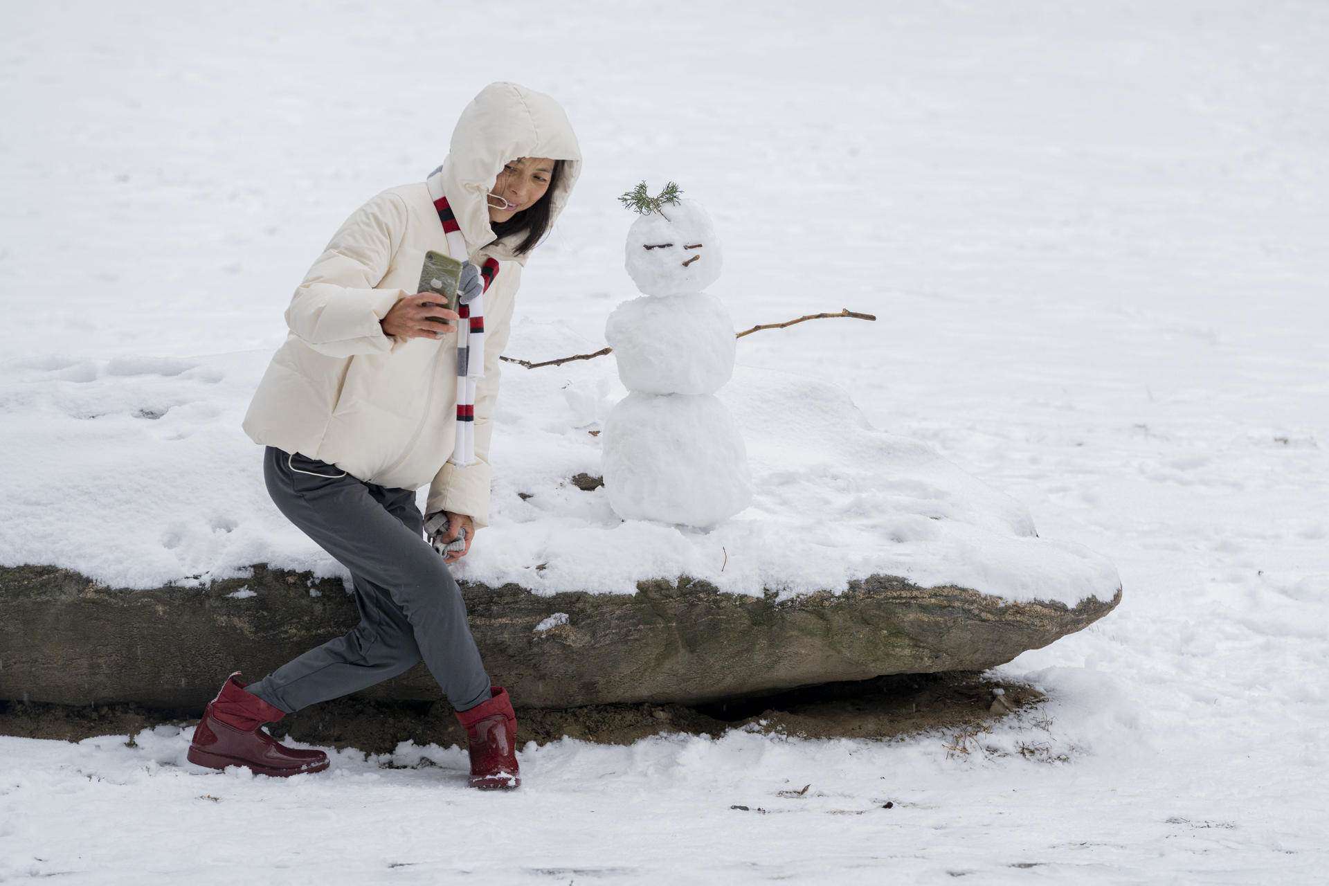 Una persona se toma una fotografía junto a un muñeco de nieve en Central Park hoy, en Nueva York (EE.UU.). 