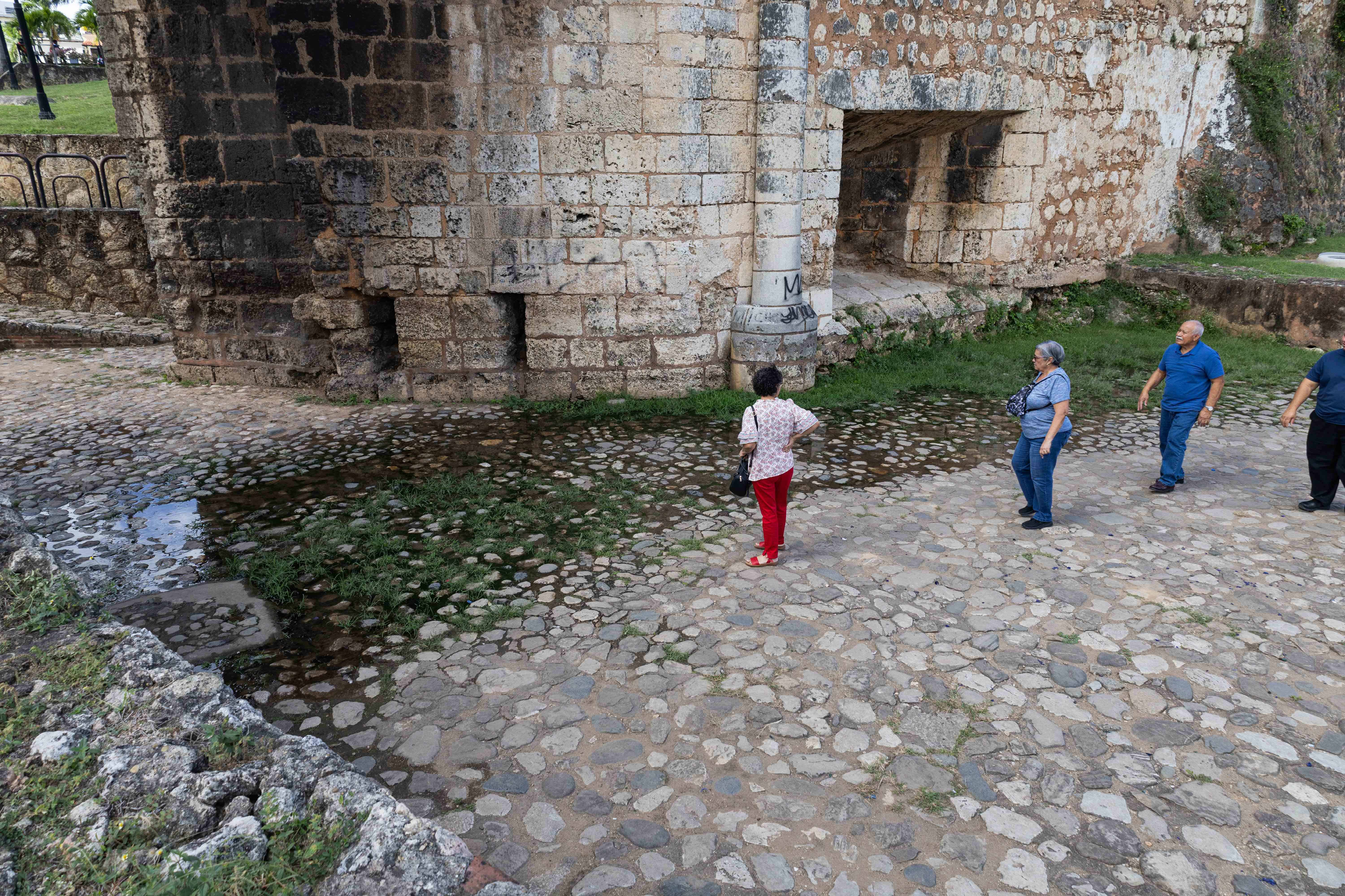 Turistas observan el lugar por donde brota agua de la que se devuelve al no encontrar salida.