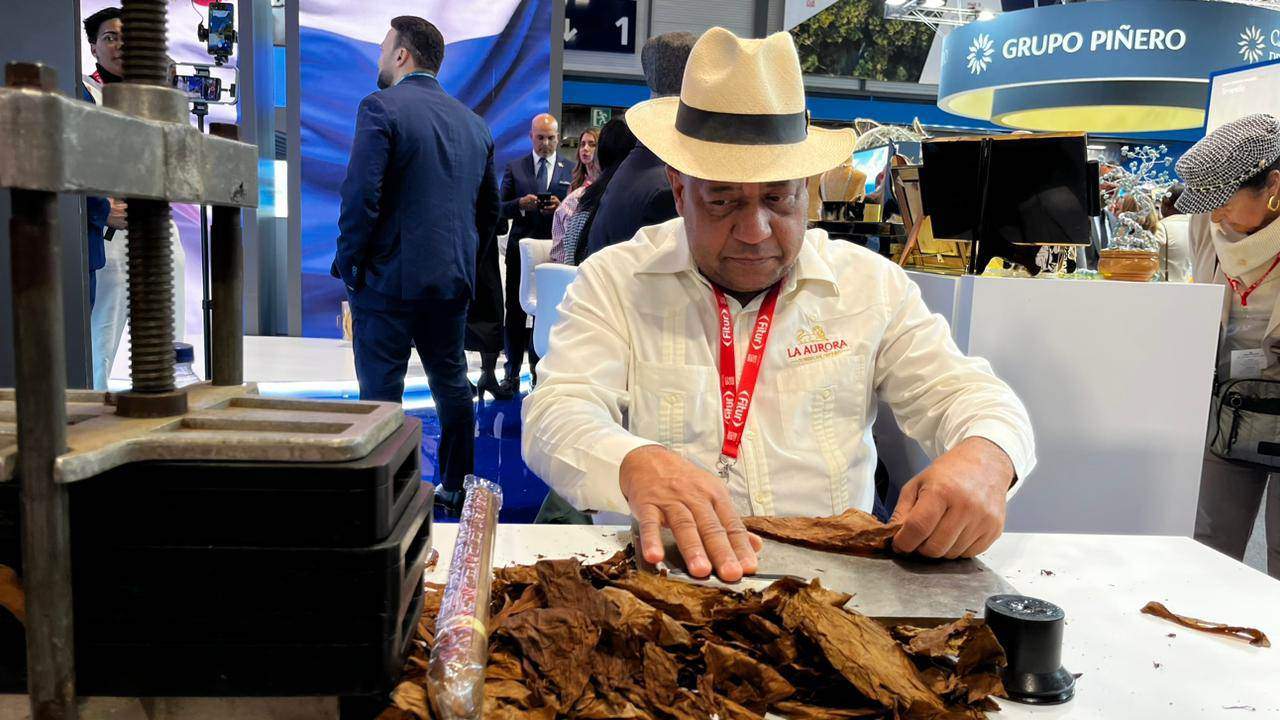 Un representante de la empresa La Aurora elabora cigarros artesanales en el estand dominicano en Fitur 2024.