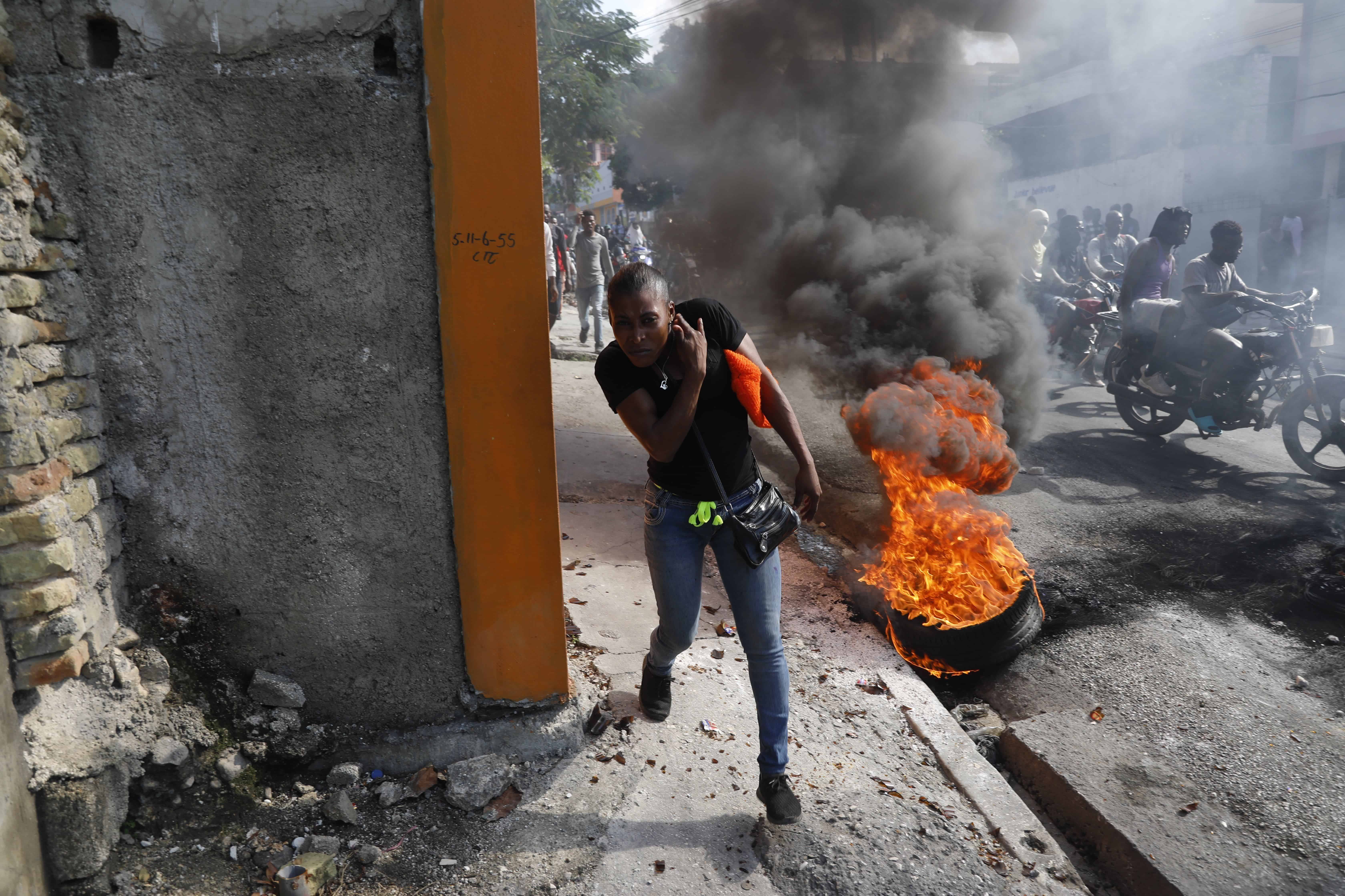 Una persona pasa junto a neumáticos en llamas mientras la gente protesta por segundo día consecutivo contra el primer ministro Ariel Henry, exigiendo su destitución, en Puerto Príncipe, Haití, el martes 6 de febrero de 2024.