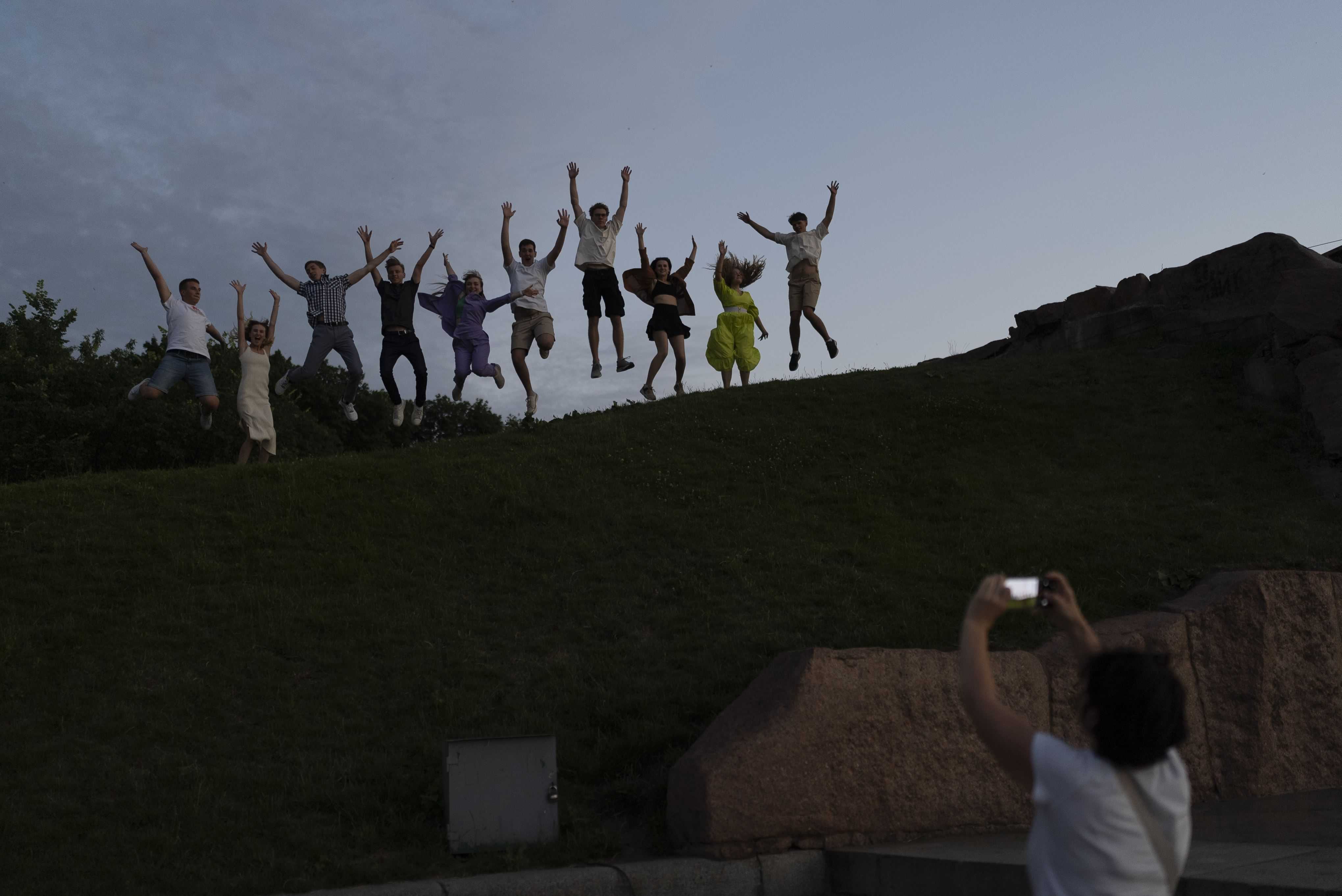 Un grupo de estudiantes de secundaria recién graduados saltan mientras posan para una foto durante la celebración, en Kiev, Ucrania, el 3 de julio de 2023.