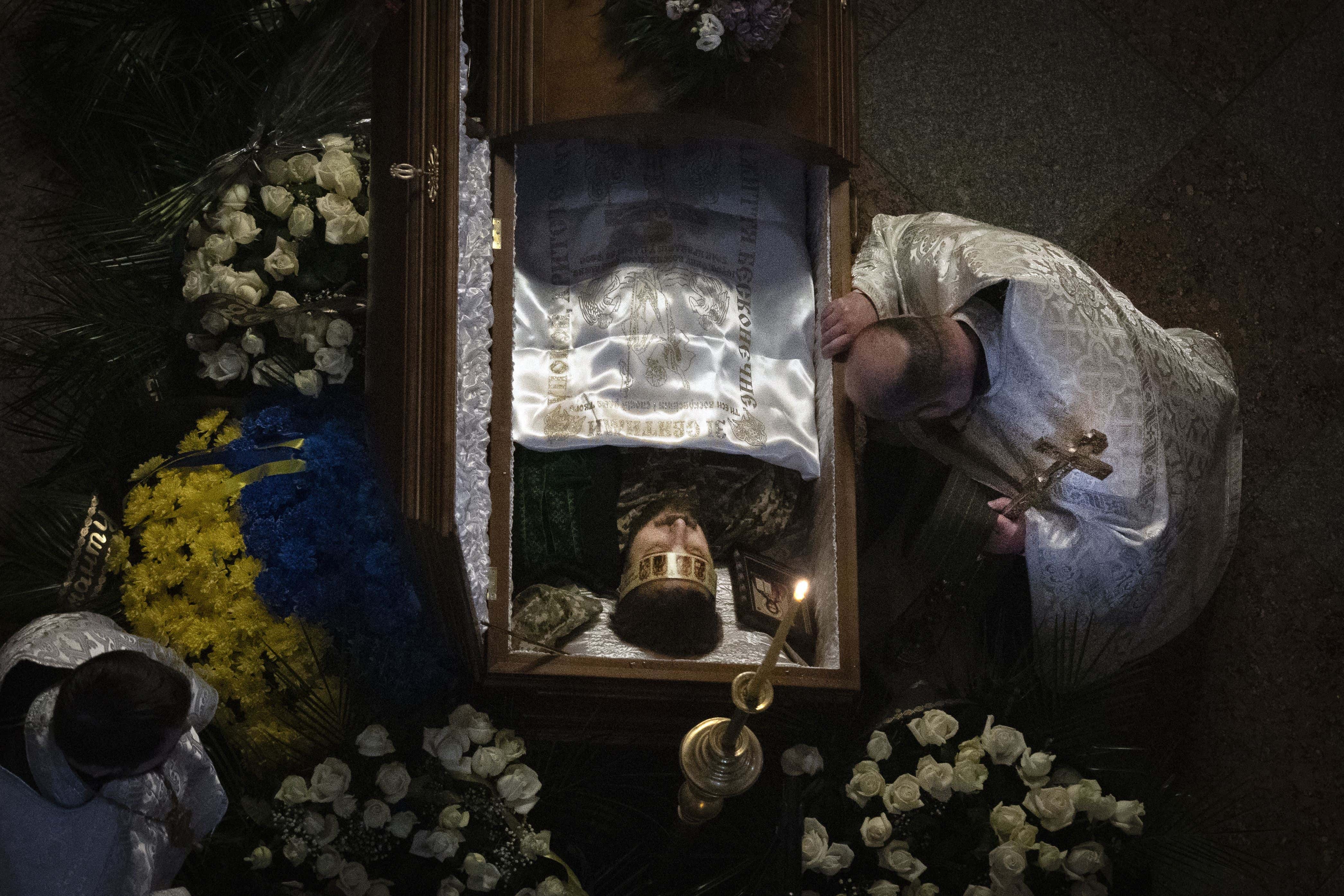 Un sacerdote reza junto al féretro del soldado y reconocido poeta Maksym Kryvtsov durante su funeral en la catedral de San Miguel, en Kiev, Ucrania, el 11 de enero de 2024.