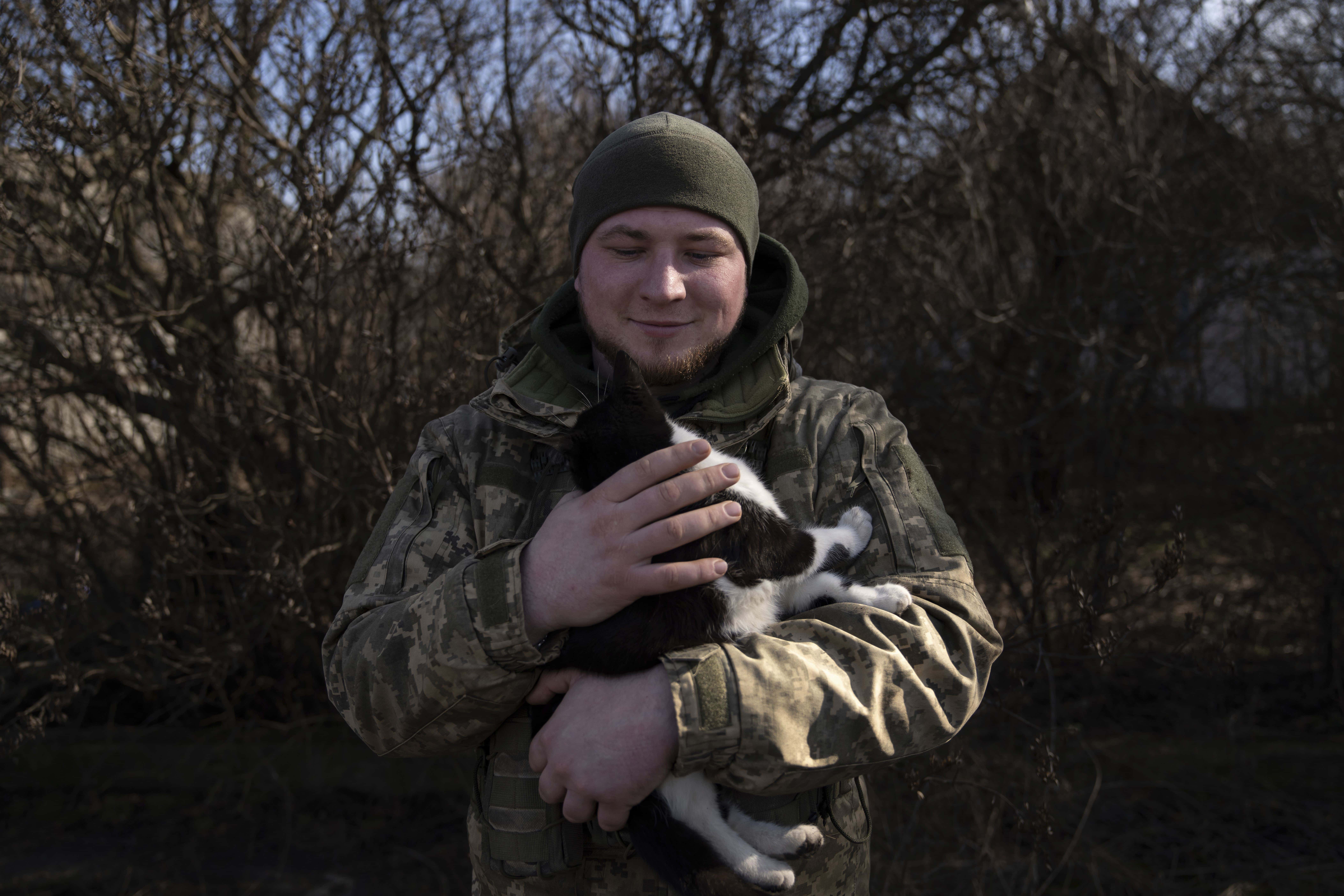 Andrii, de 25 años, un comandante ucraniano de la tripulación Grad, acaricia a un gato mientras espera órdenes del centro de comando en la línea del frente en la región de Donetsk, Ucrania, el viernes 23 de febrero.