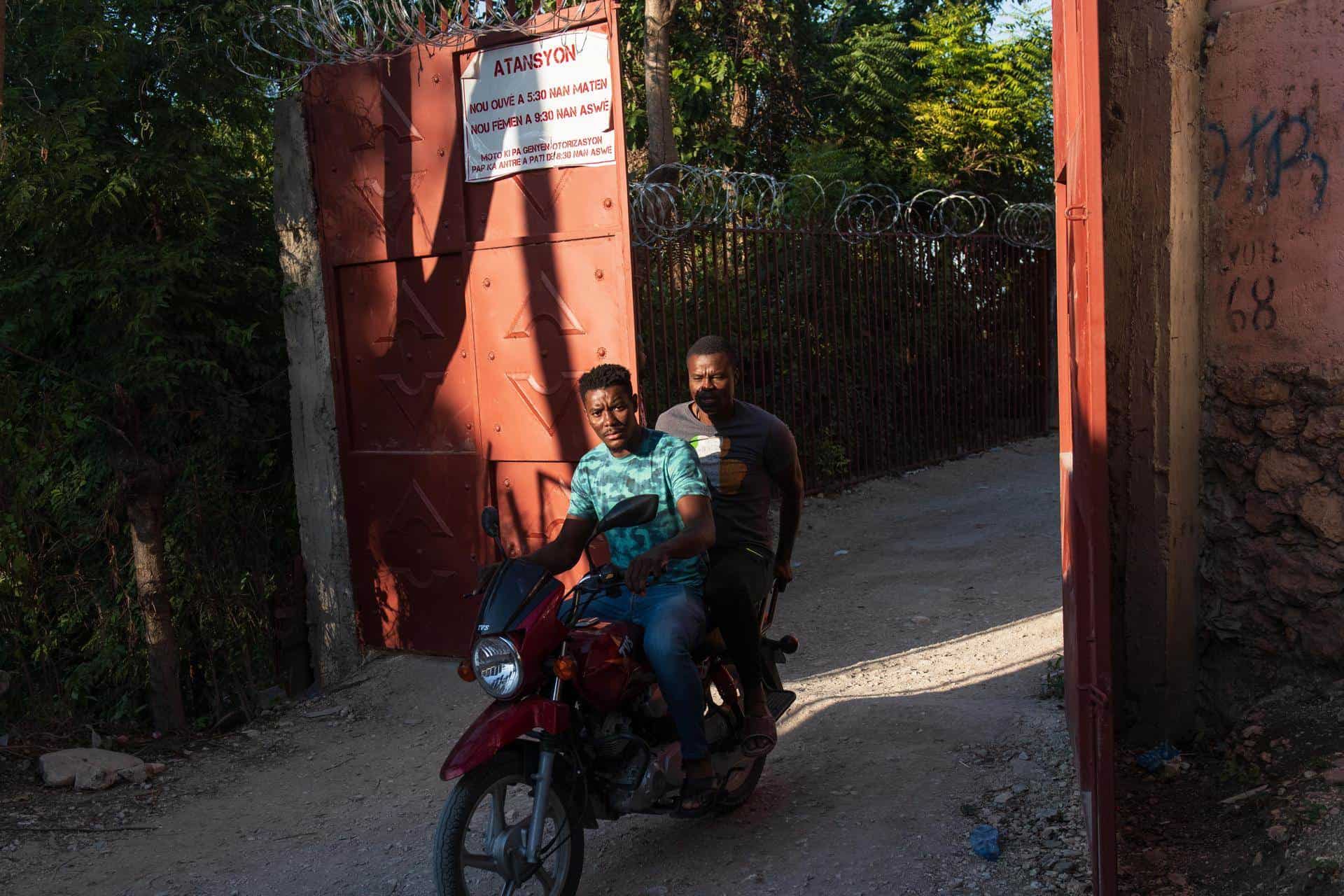 Dos hombres en motocicleta cruzan una de las barreras que vecinos de muchas calles han instalado para protegerse de la violencia de las pandillas, este domingo en Puerto Príncipe (Haití).