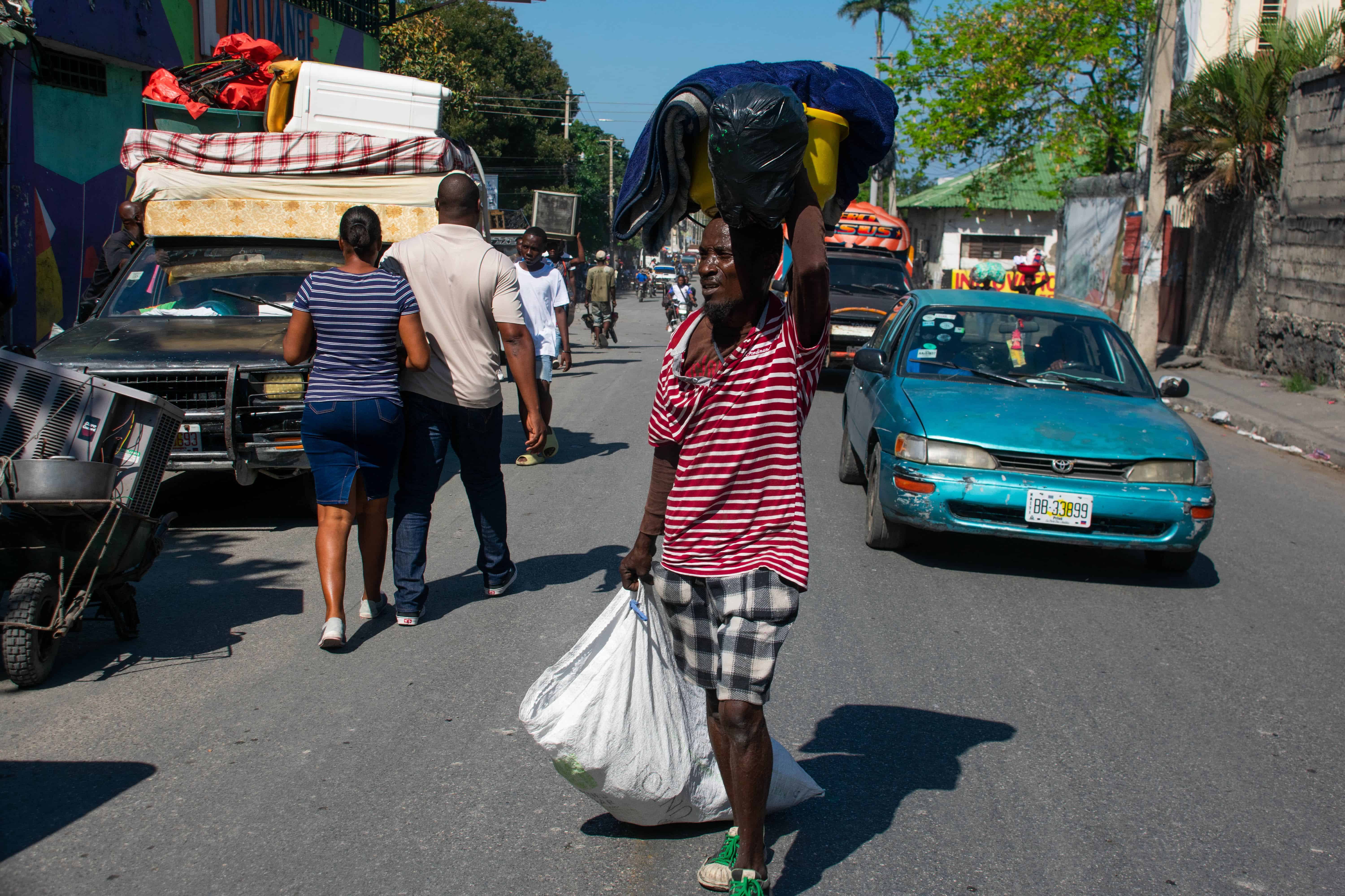 Personas con sus pertenencias salen de los alrededores de la Penitenciaria Nacional luego del ataque por parte de bandas armadas, este domingo en Puerto Príncipe (Haití).