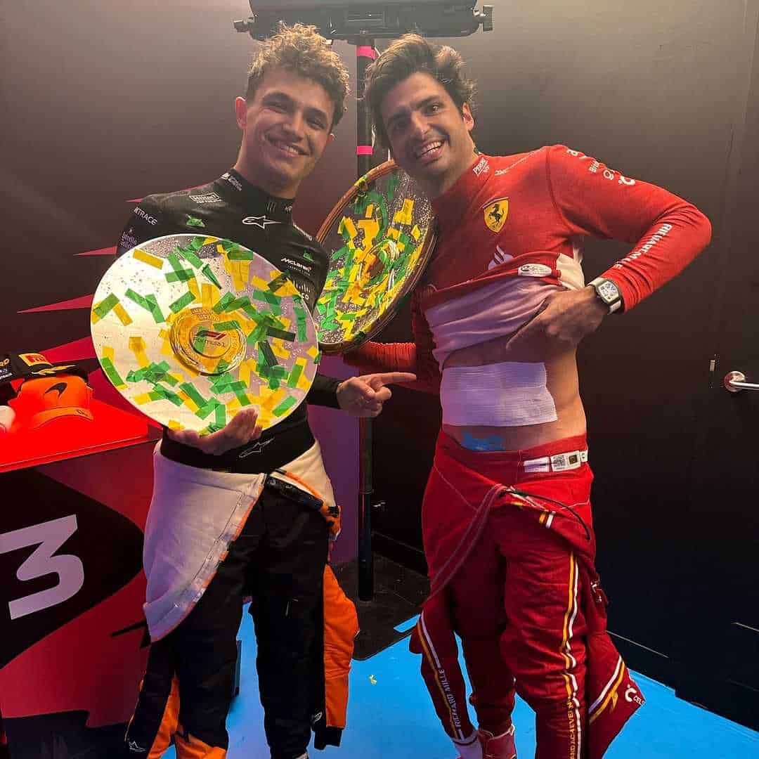 Lando Norris y Carlos Sainz celebran el podio mientras el español enseña la zona donde le operaron