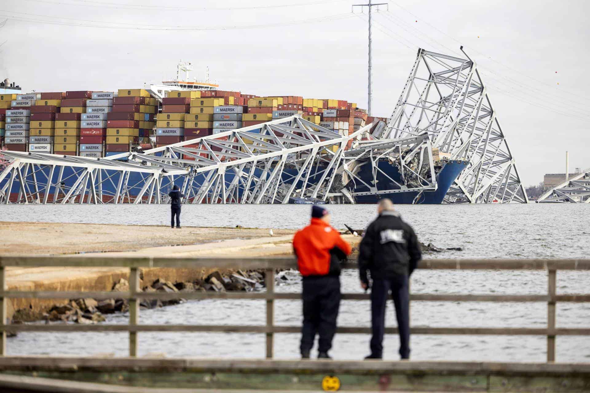 Dos personas, observando el buque y el puente de Baltimore.