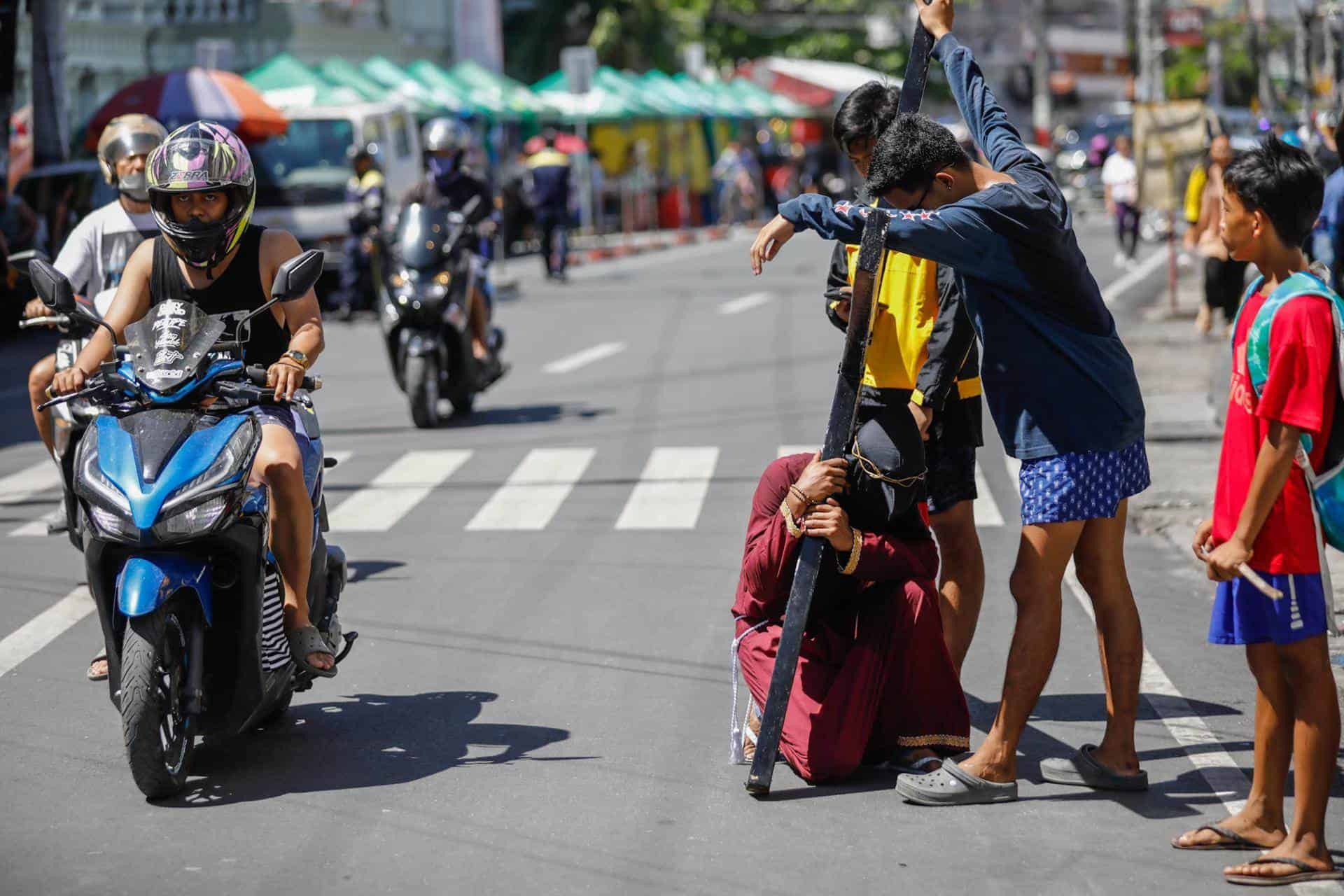 Un penitente católico se arrodilla para descansar de llevar una cruz de madera a lo largo de las calles para conmemorar el Jueves Santo en la ciudad de San Fernando, provincia de Pampanga, Filipinas, 28 de marzo de 2024.