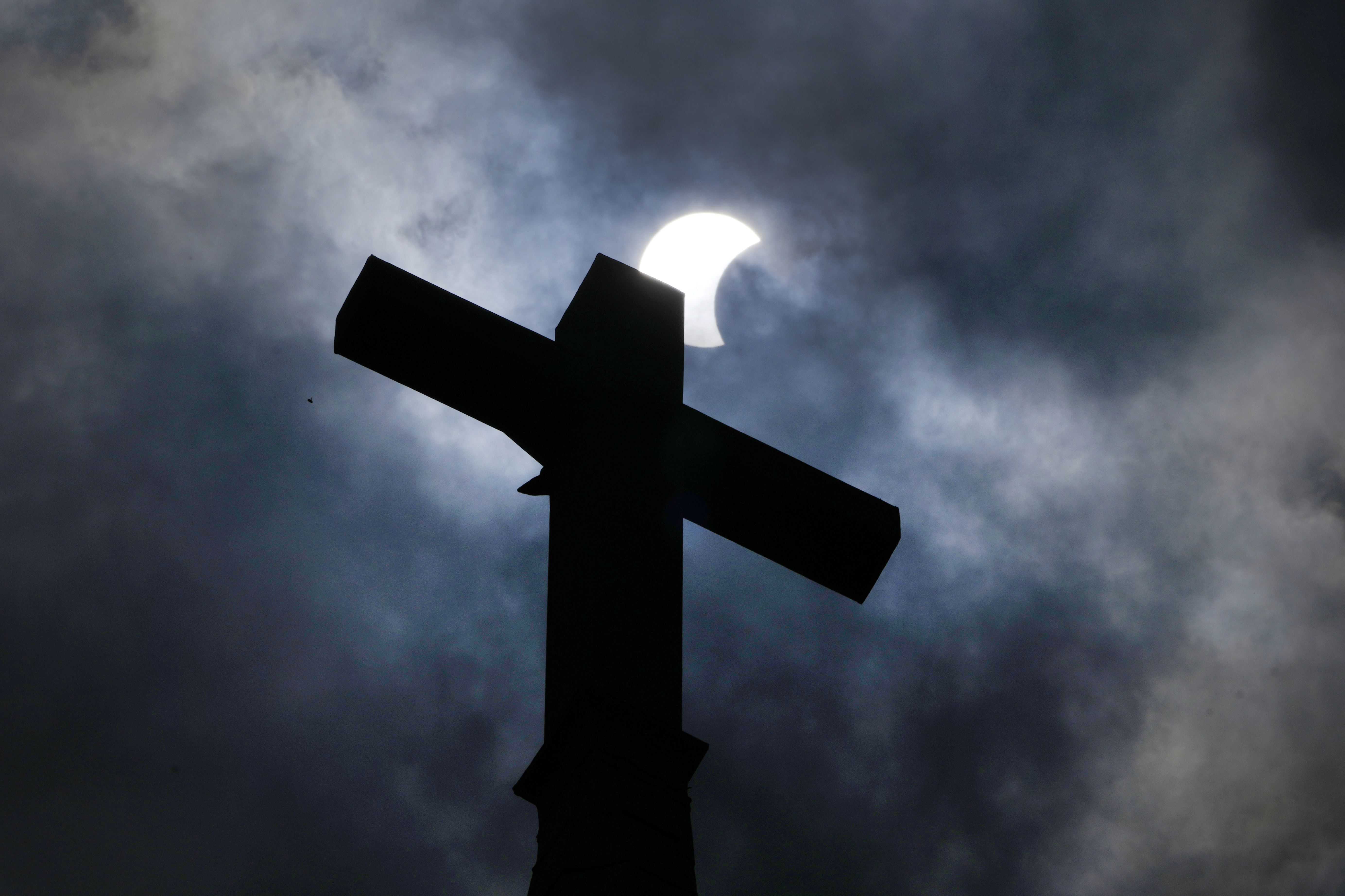 Las nubes se separan cuando un eclipse parcial de sol y luna se cruza sobre el campanario de la Iglesia Evangélica Luterana de Nueva Suecia el lunes 8 de abril de 2024 en Manor, Texas.