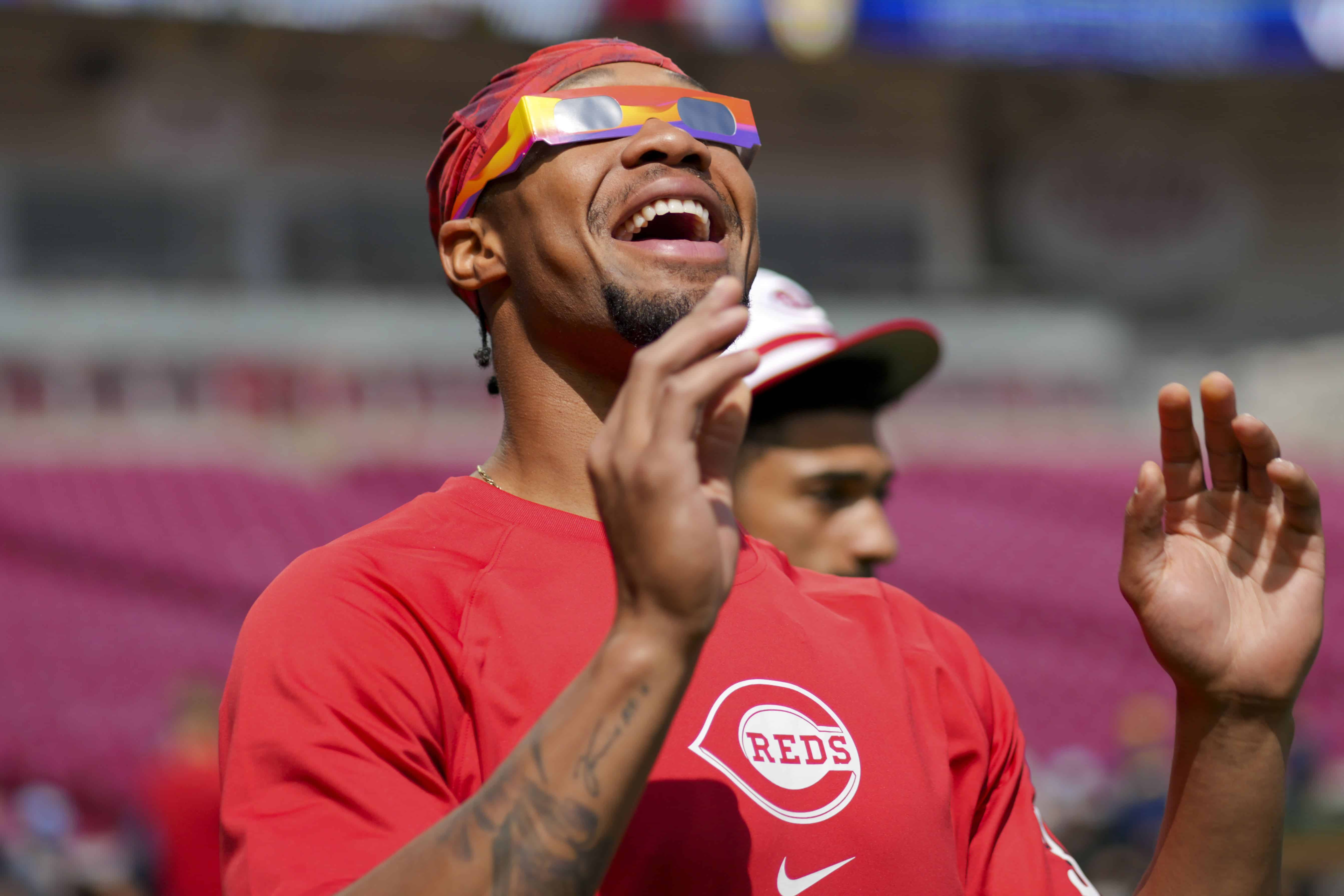 Will Benson, de los Rojos de Cincinnati, reacciona al sol durante un eclipse solar antes de un partido de béisbol contra los Cerveceros de Milwaukee en Cincinnati, el lunes 8 de abril de 2024.
