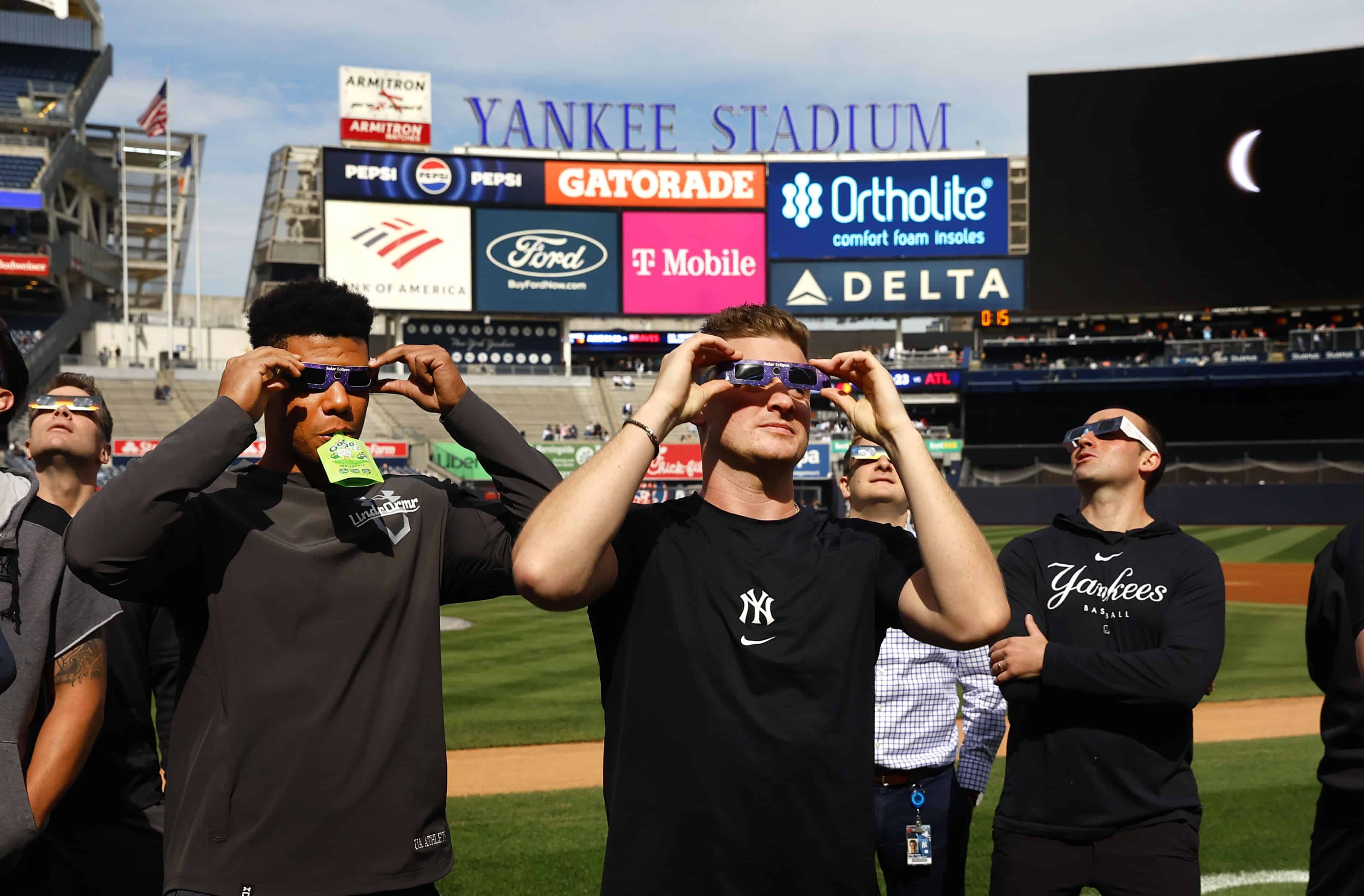 Juan Soto, izquierda, y Clarke Schmidt, derecha, de los Yankees de Nueva York, observan el eclipse solar total desde el Yankee Stadium. Lunes 8 de abril de 2024 en Nueva York.