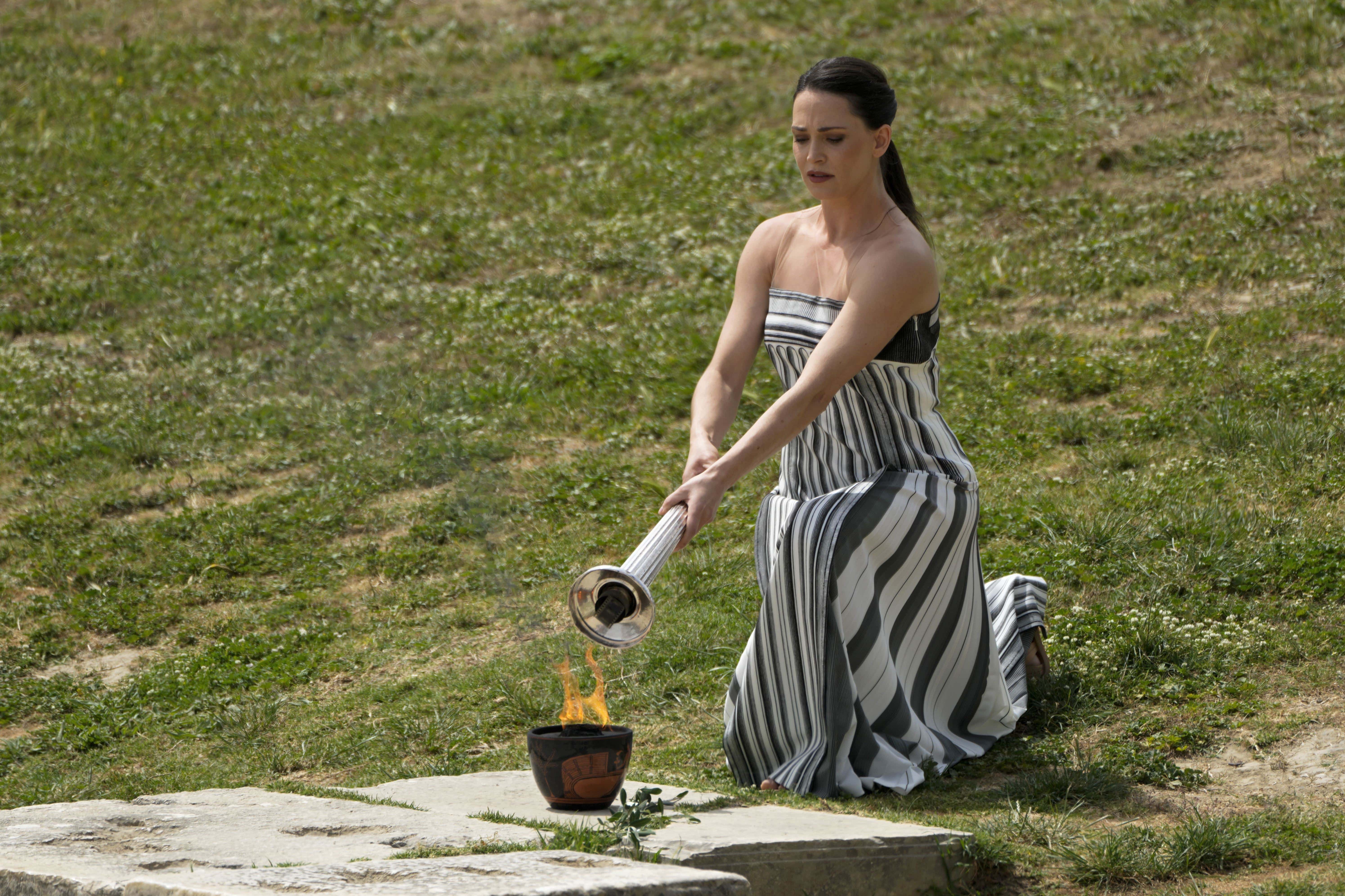 La actriz Mary Mina, interpretando a la suma sacerdotisa, enciende una antorcha con una llama encendida el día anterior durante la ceremonia oficial de encendido de la llama de los Juegos Olímpicos de París.